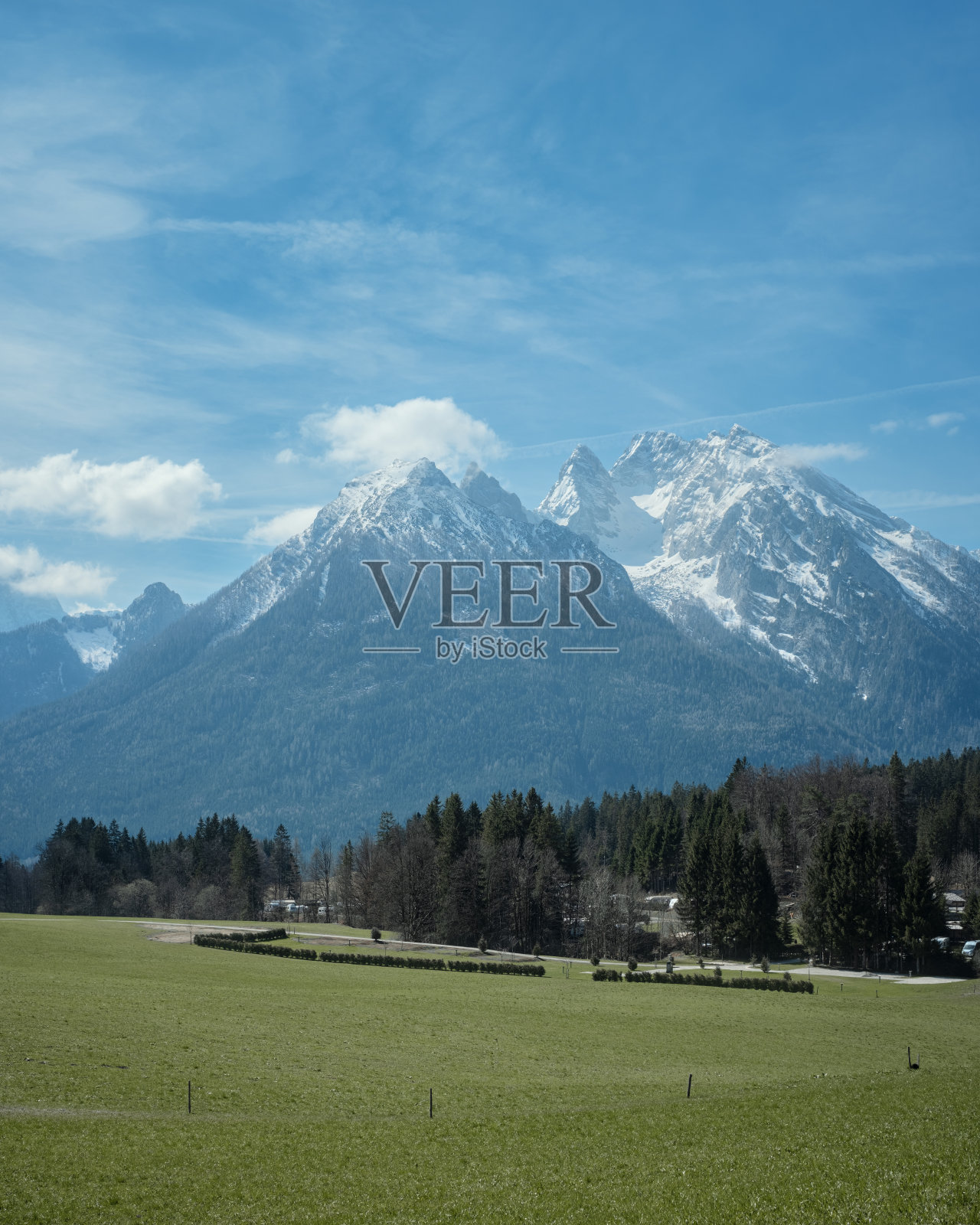 在一个美丽的阳光灿烂的日子里，在阿尔卑斯山的清新的绿色草地上，欣赏田园般的山景照片摄影图片