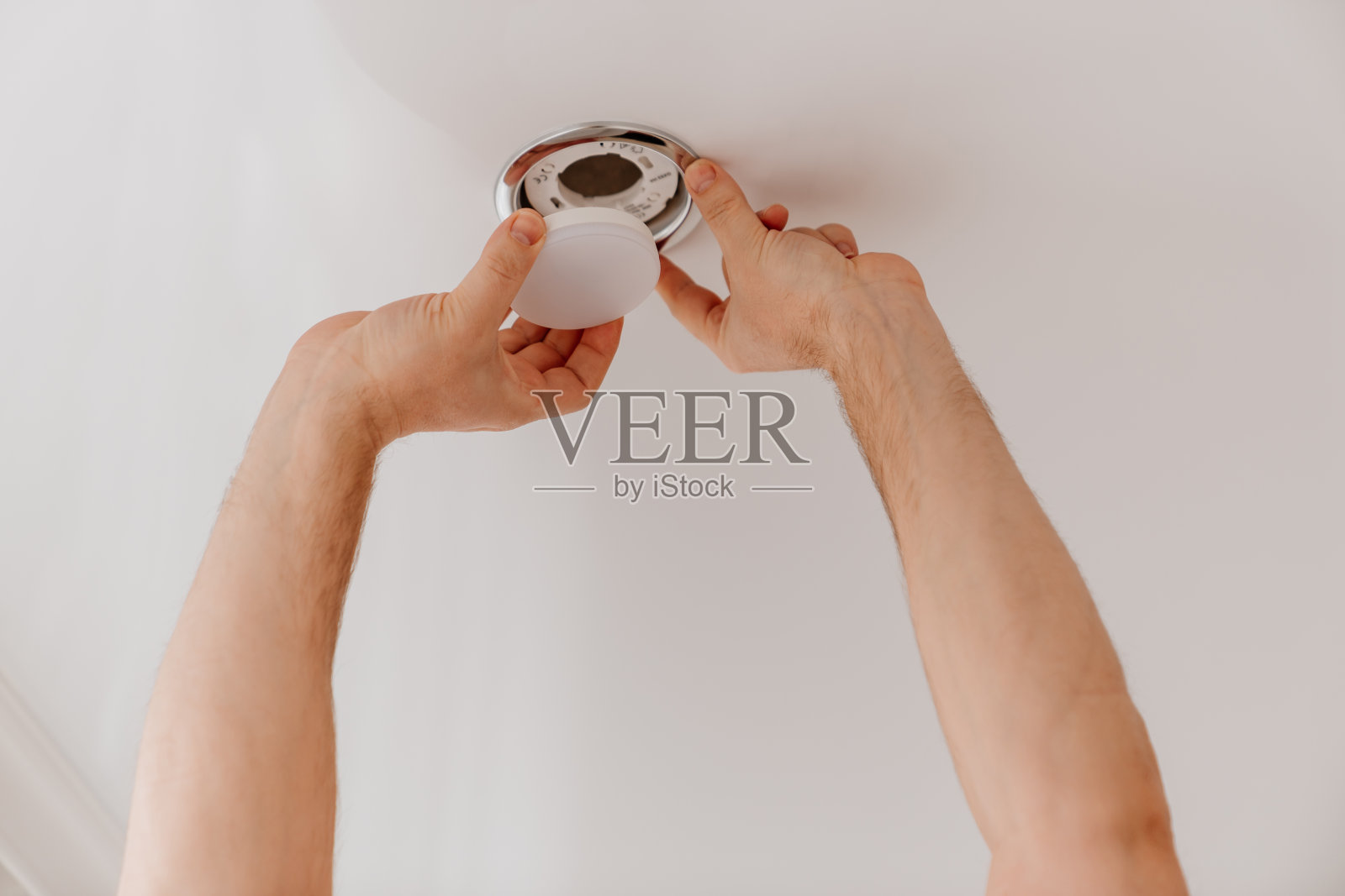 一名男性电工正在更换聚光顶灯的灯泡照片摄影图片