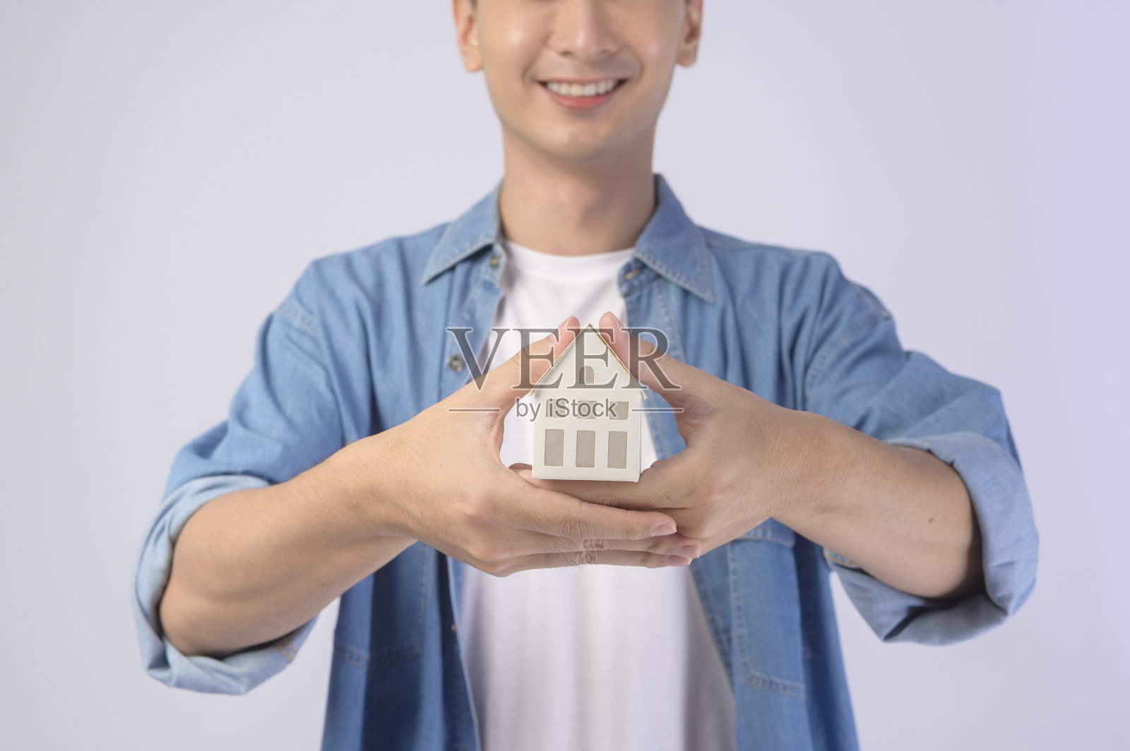年轻微笑的男子在白色背景的工作室抱着小模型房子照片摄影图片