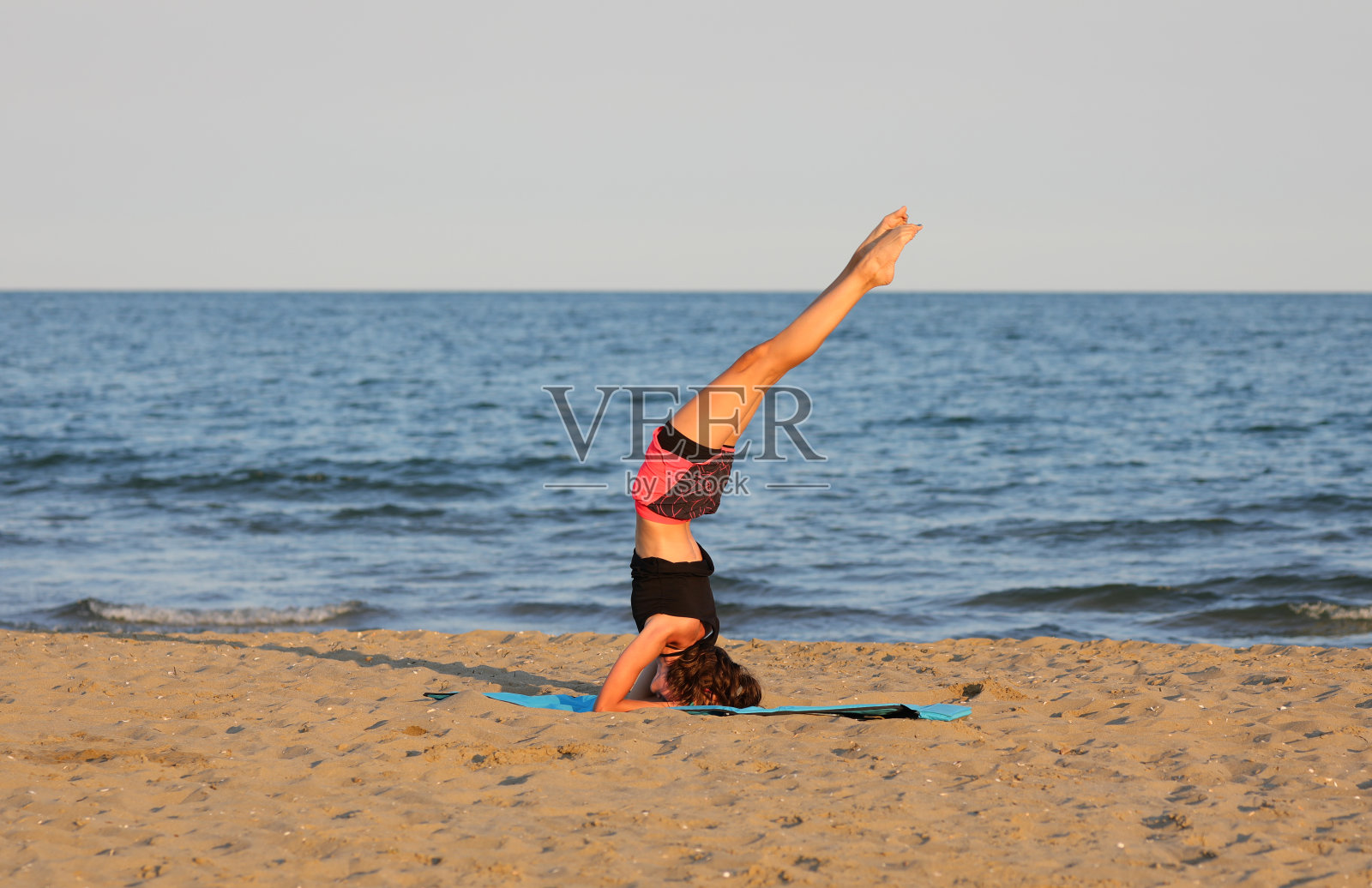 夏天，年轻苗条的女孩穿着超短裤在海边做体操照片摄影图片