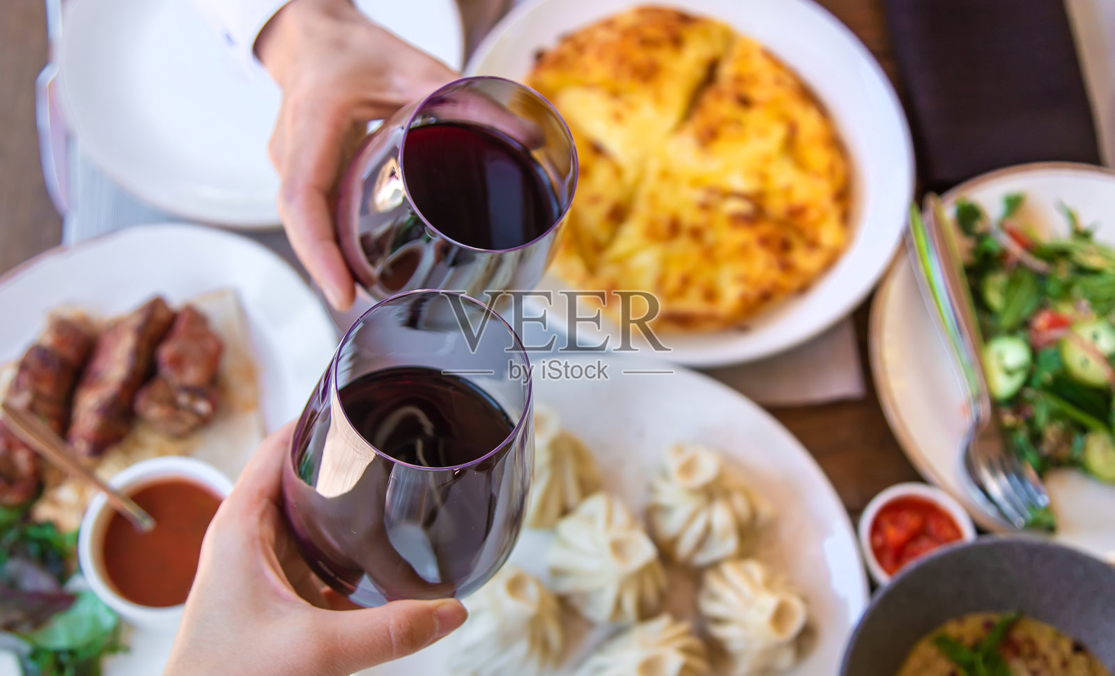 格鲁吉亚餐厅菜上桌，酒在手。有选择性的重点。照片摄影图片