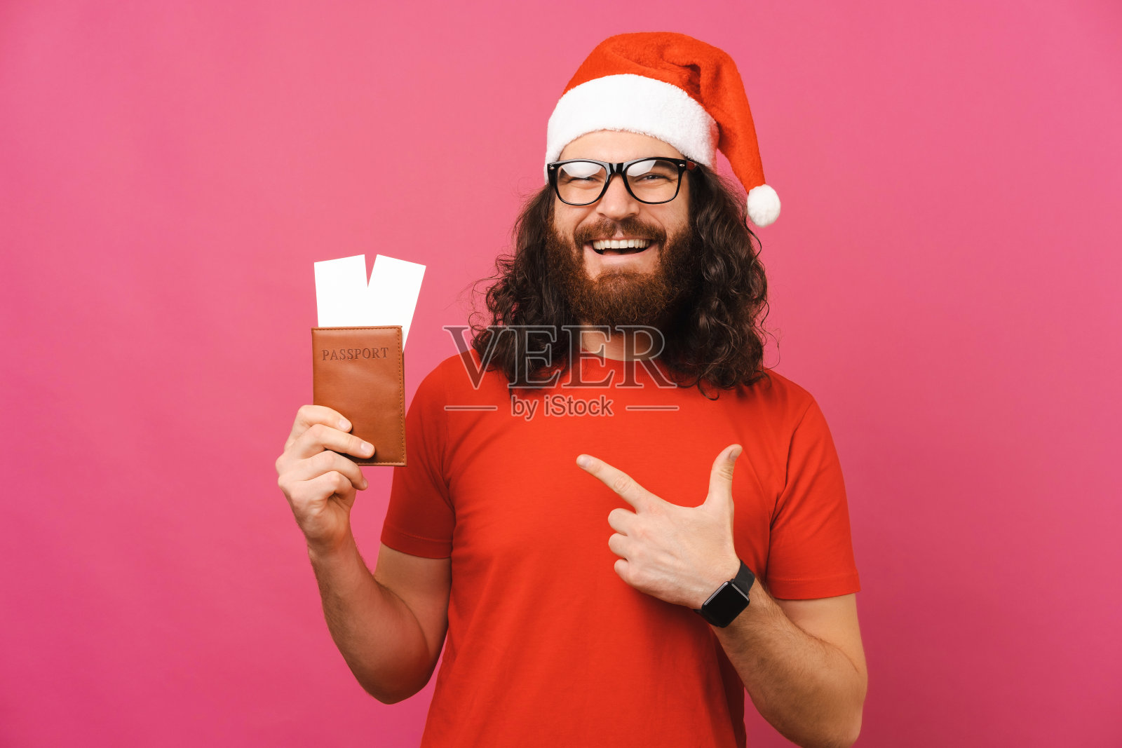 戴着圣诞帽的胡子男正指着一张有票的护照。照片摄影图片
