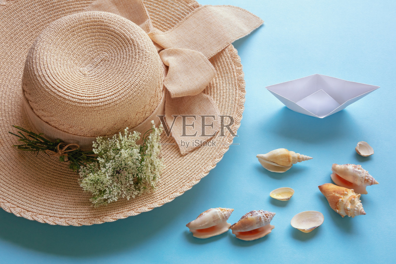 暑假和假期的概念。太阳帽、野花、白色纸船和蓝色背景下的贝壳。本空间照片摄影图片