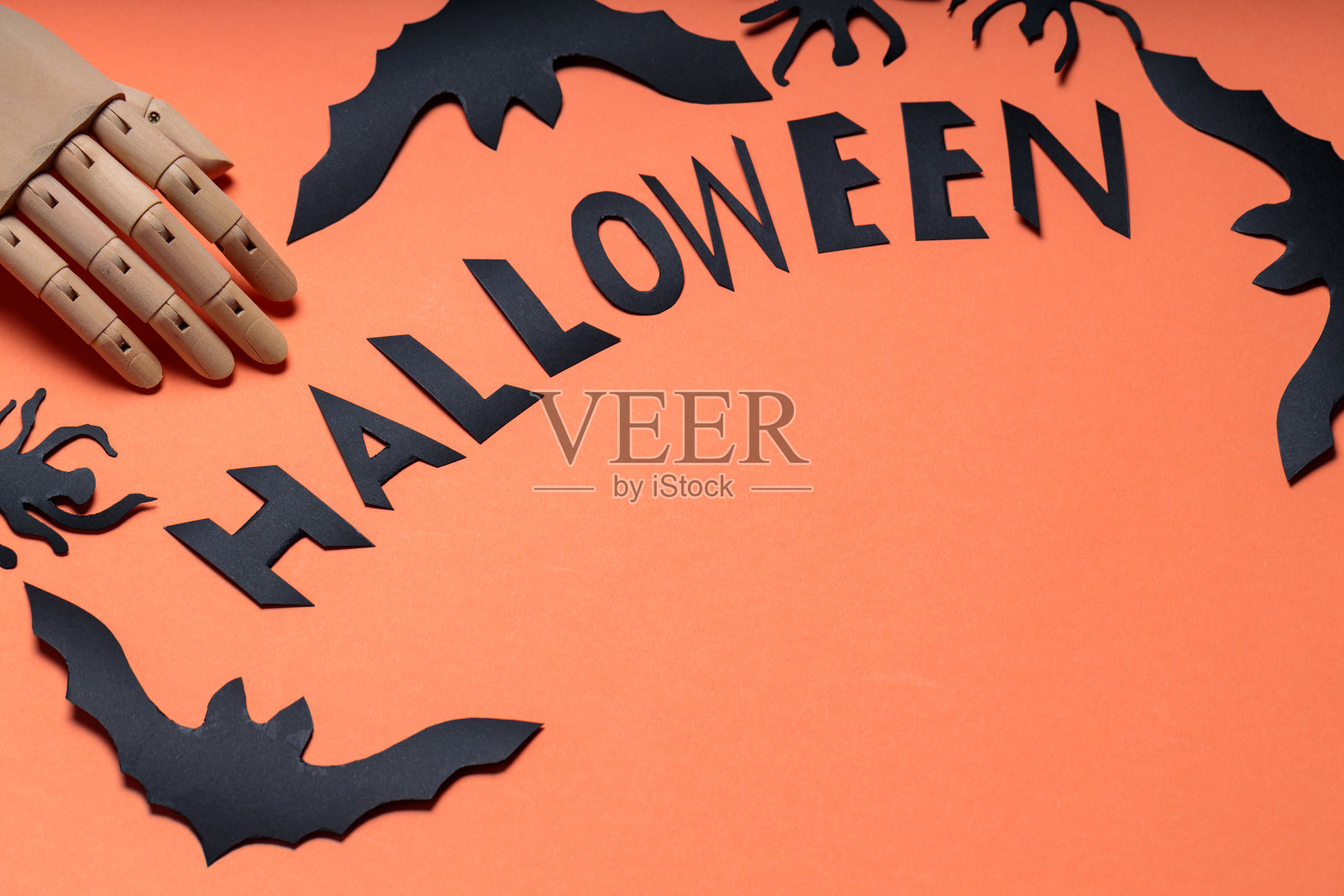 万圣节的概念与人工手臂，蝙蝠和蜘蛛在橙色的背景。万圣节用木手和蝙蝠的图案书写。本空间照片摄影图片