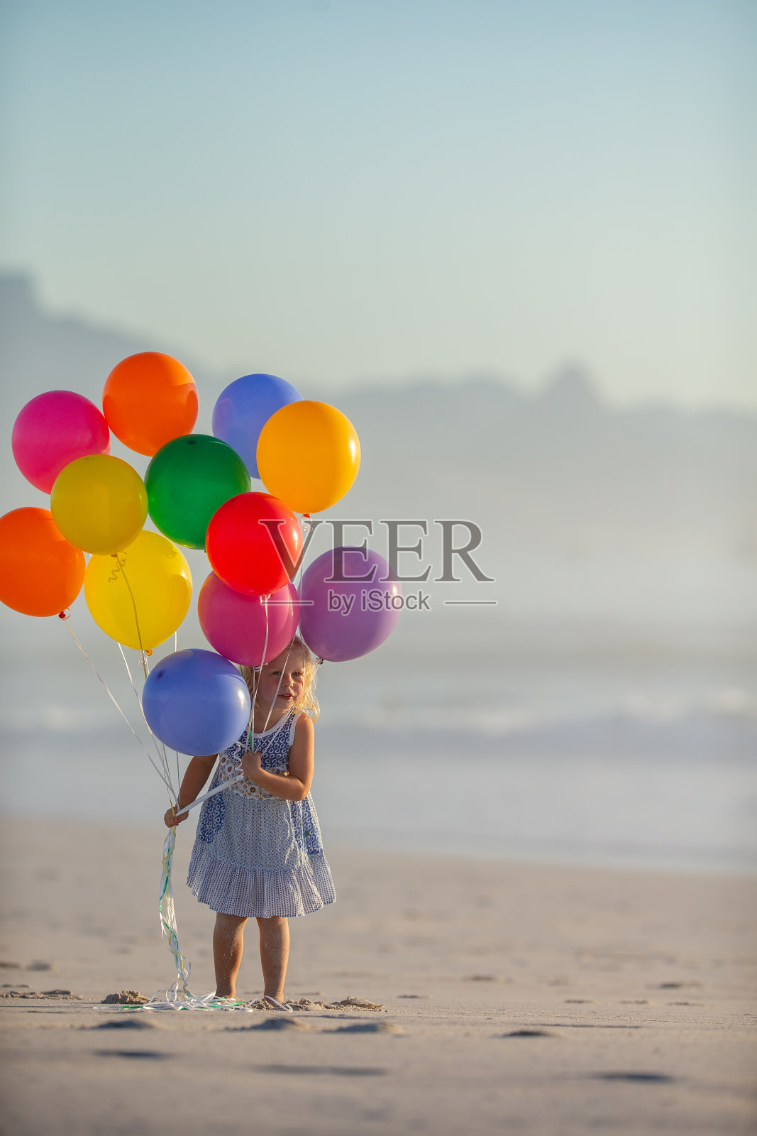 小女孩和她的一堆彩色气球在海滩上享受节日的一天照片摄影图片