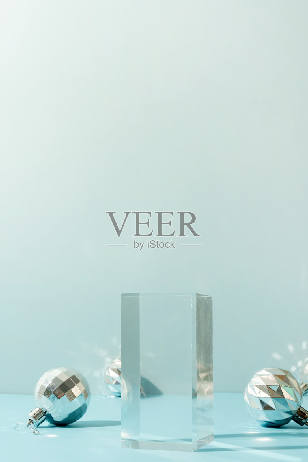 一个极简的场景的玻璃讲台与圣诞装饰球在浅蓝色的背景照片摄影图片