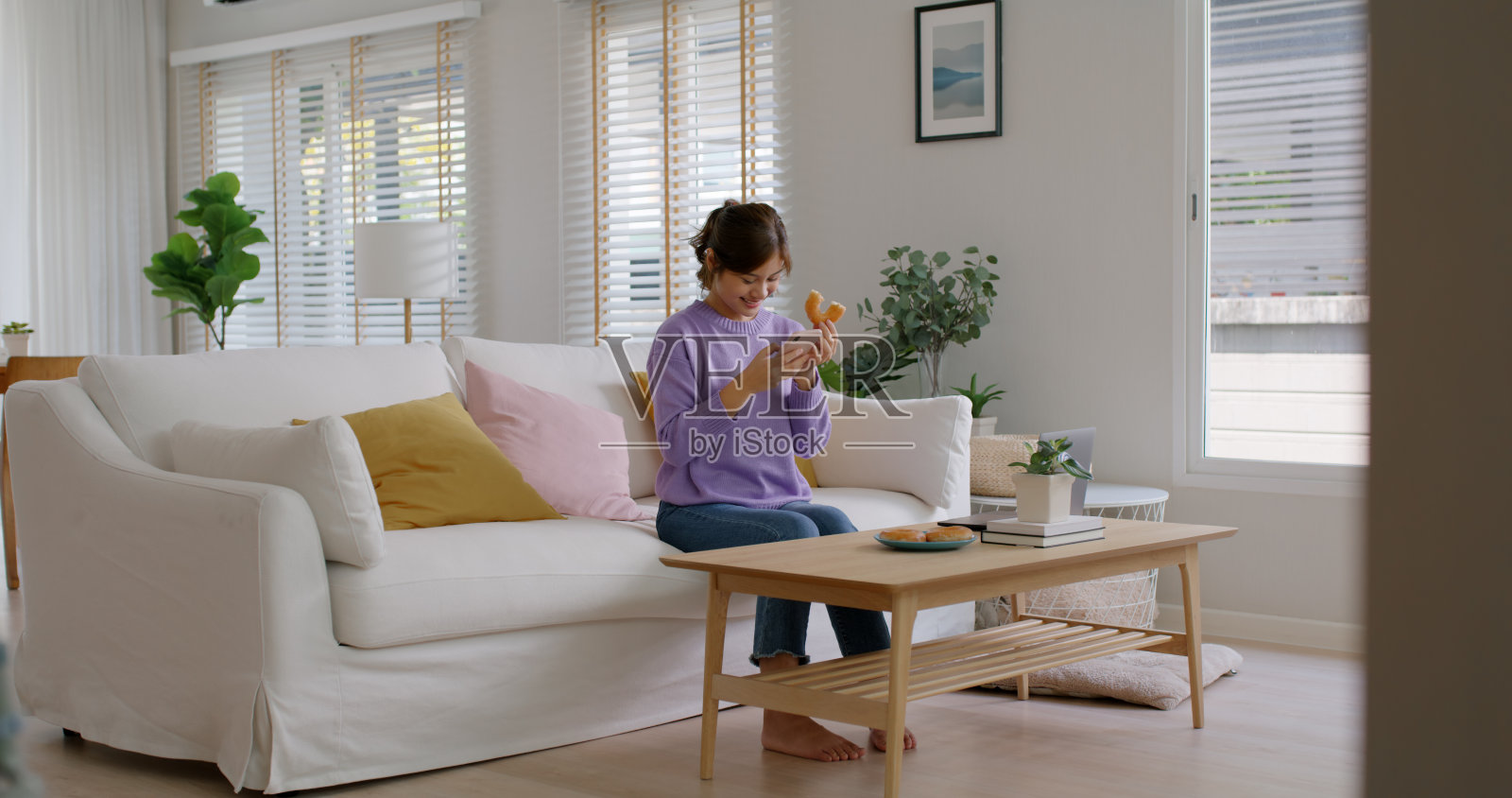 年轻的视频博主亚洲人网红女孩拍照吃咬笑脸甜甜圈搞笑的脸在instagram上发布评论抖音卷应用程序甜牙食物糖爱好者享受乐趣展示在家里的病毒式摄像机。照片摄影图片