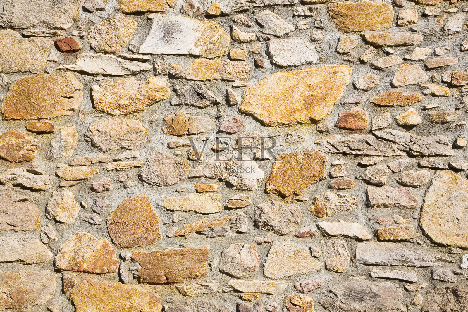 用不规则形状的石块建造的旧墙最近得到了修复照片摄影图片