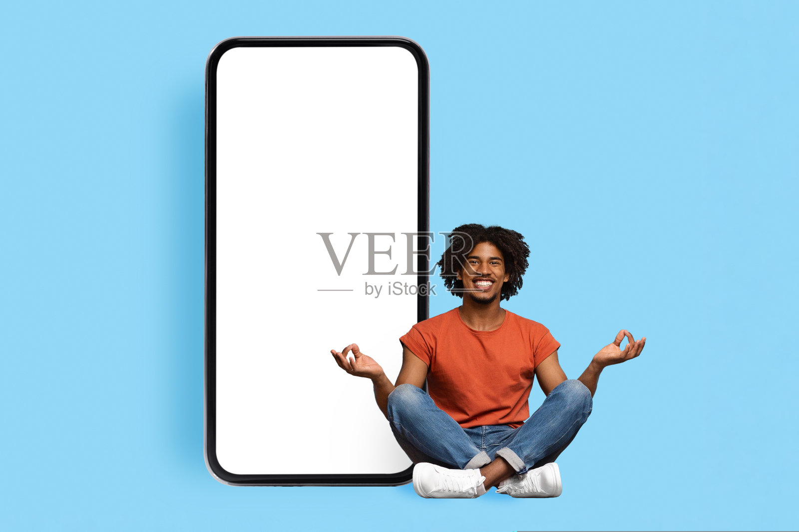 和平的黑人在大手机旁边冥想，模型照片摄影图片