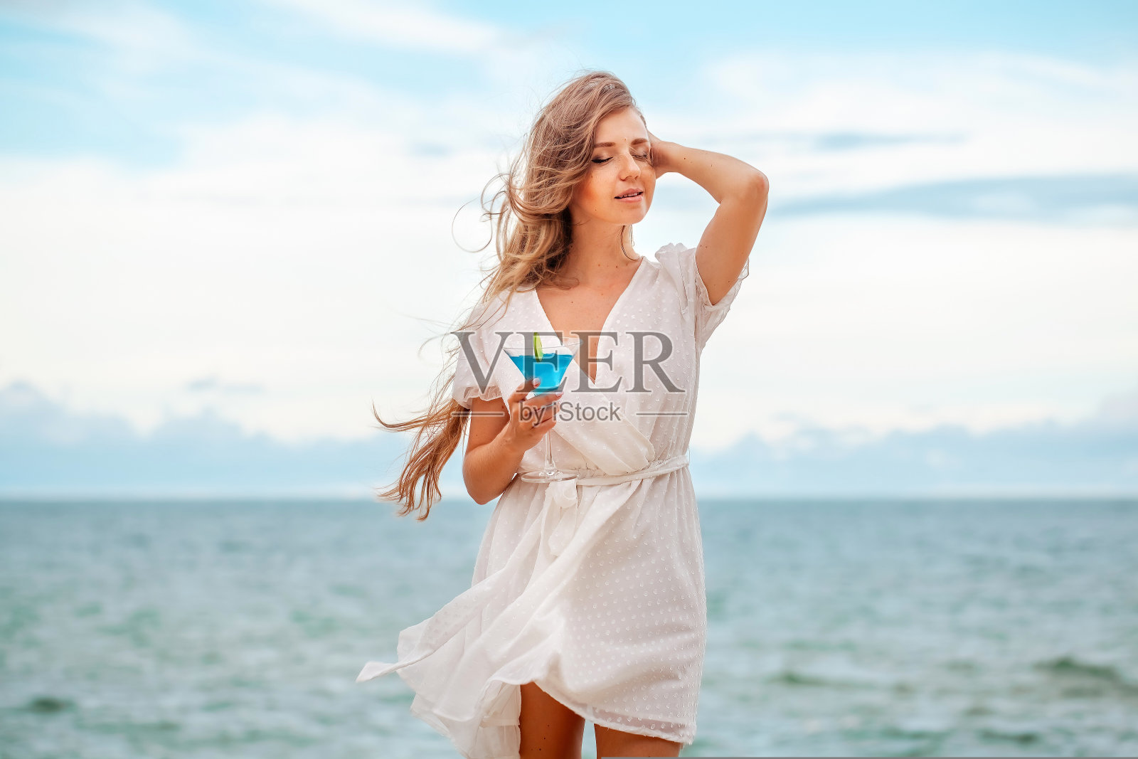 傍晚时分，女人在海边的户外酒吧里享受鸡尾酒照片摄影图片