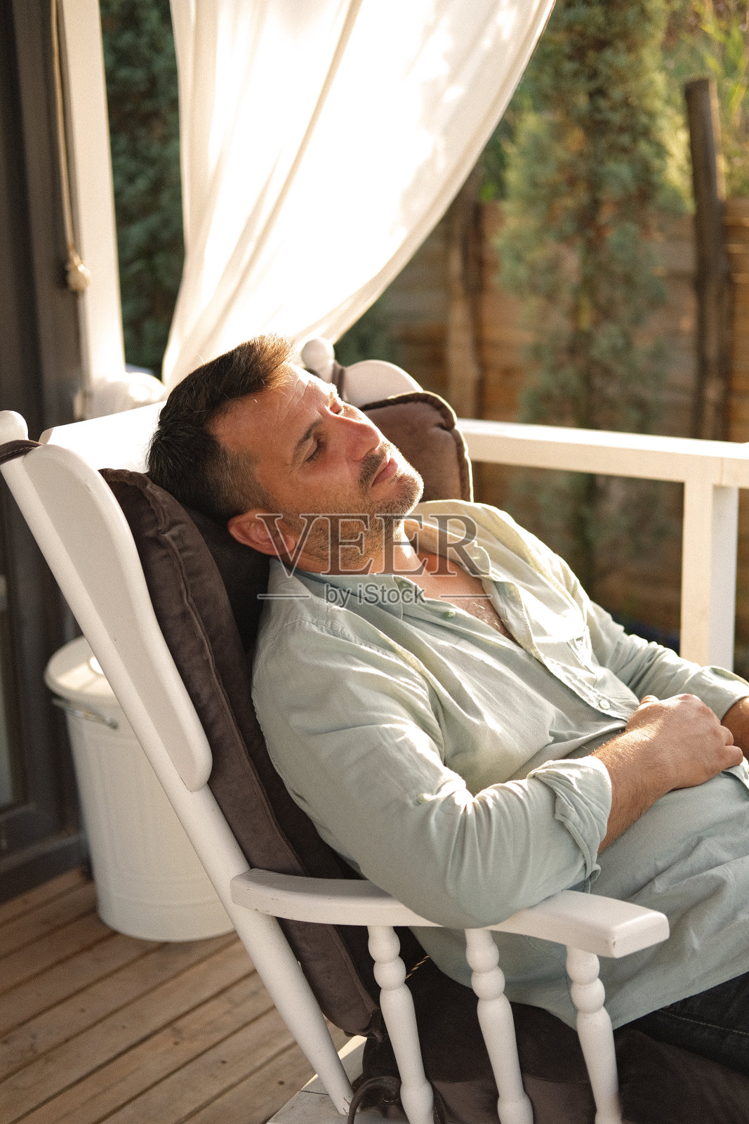 一名穿着便装的男子在田园诗般的乡村花园用笔记本电脑工作。照片摄影图片