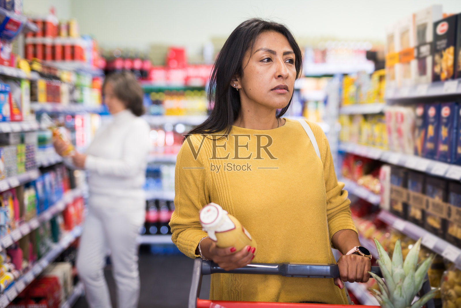 在杂货店里推着购物车的西班牙妇女照片摄影图片