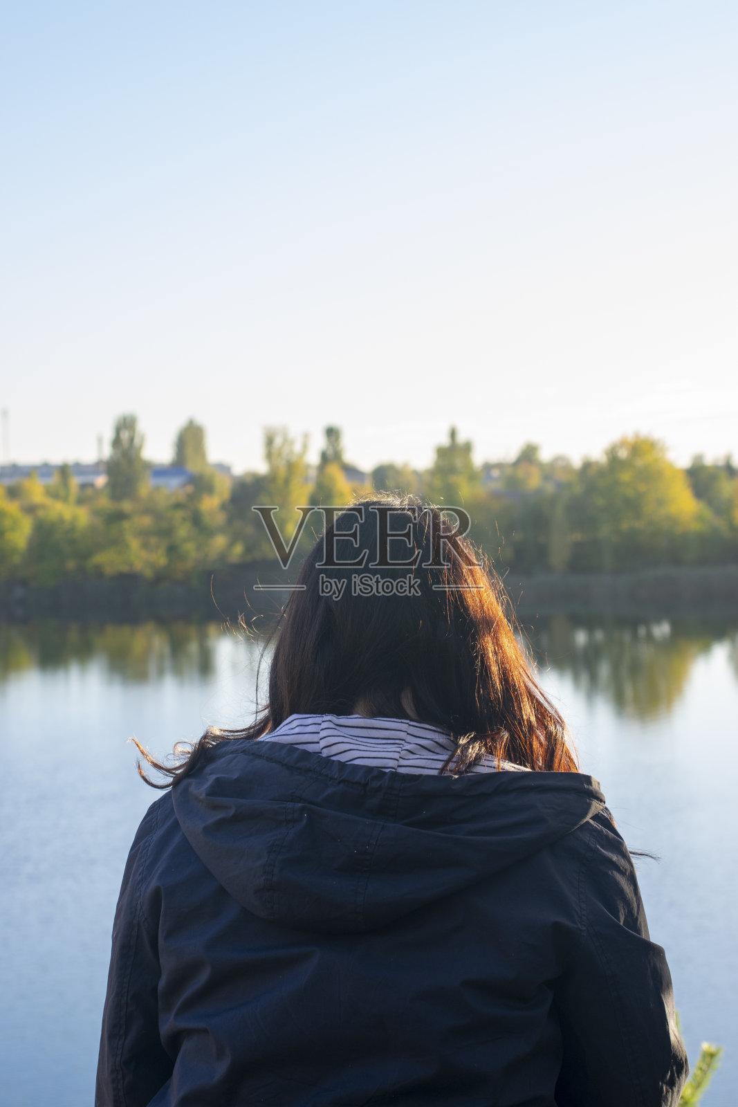 女孩独自坐在湖边的岩石上照片摄影图片