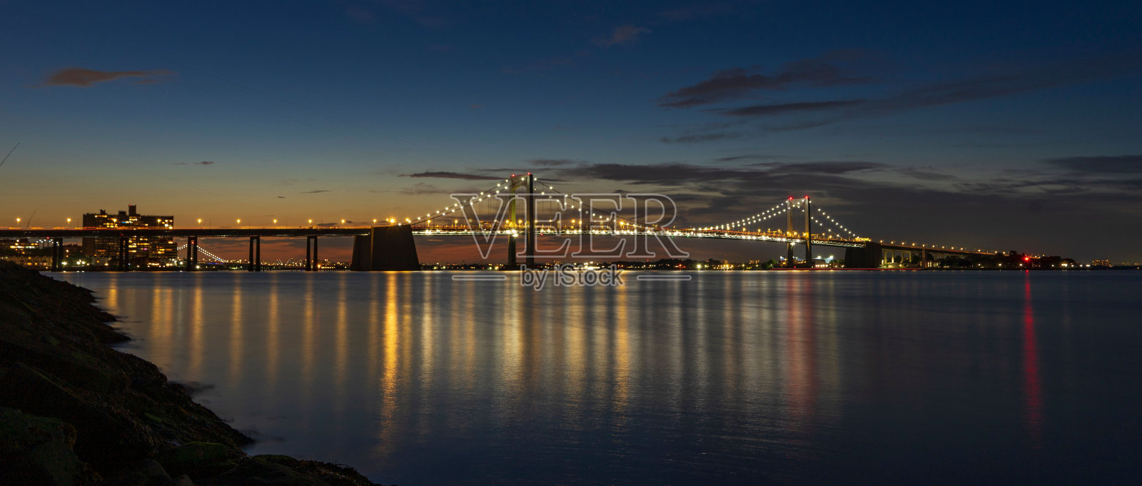 美丽的大海，背景是一座被照亮的桥和日落的天空照片摄影图片