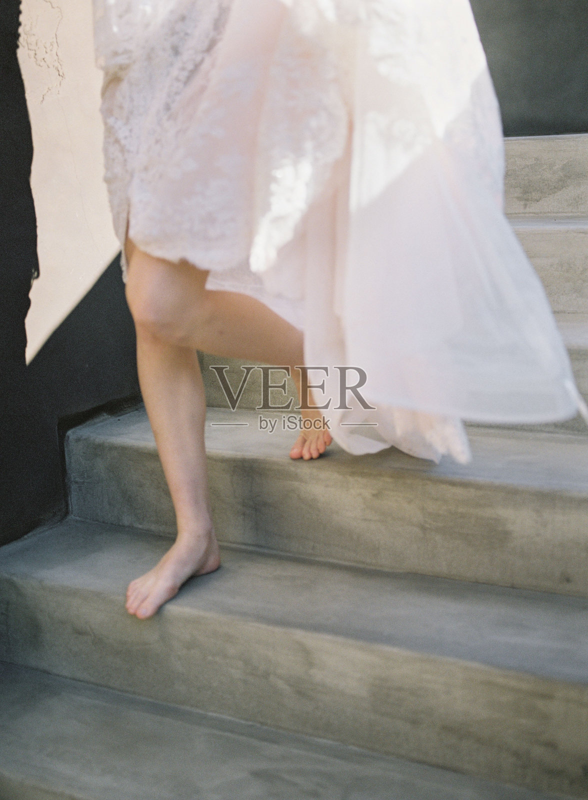 光着脚的女人穿着白色的裙子走下楼梯在混凝土楼梯上照片摄影图片