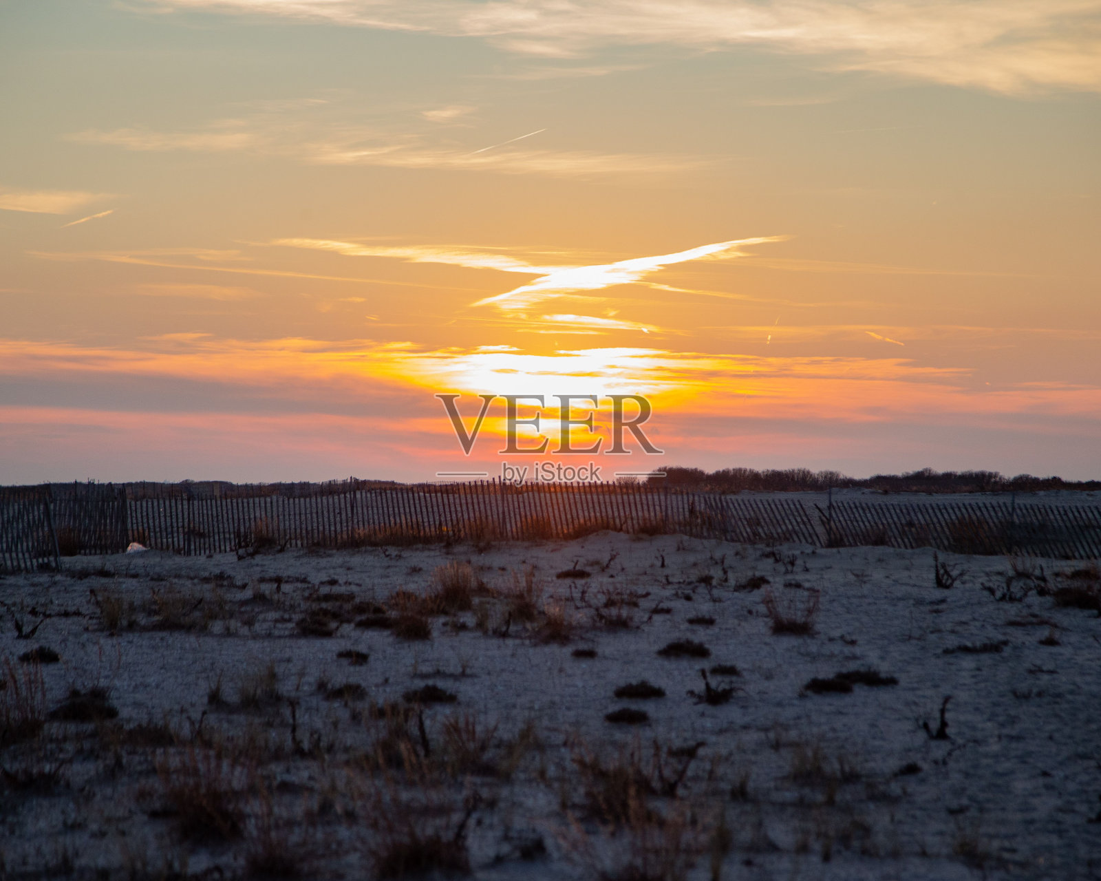 在干燥的农村地区，明亮的橙色太阳落在地平线上的风景照片照片摄影图片