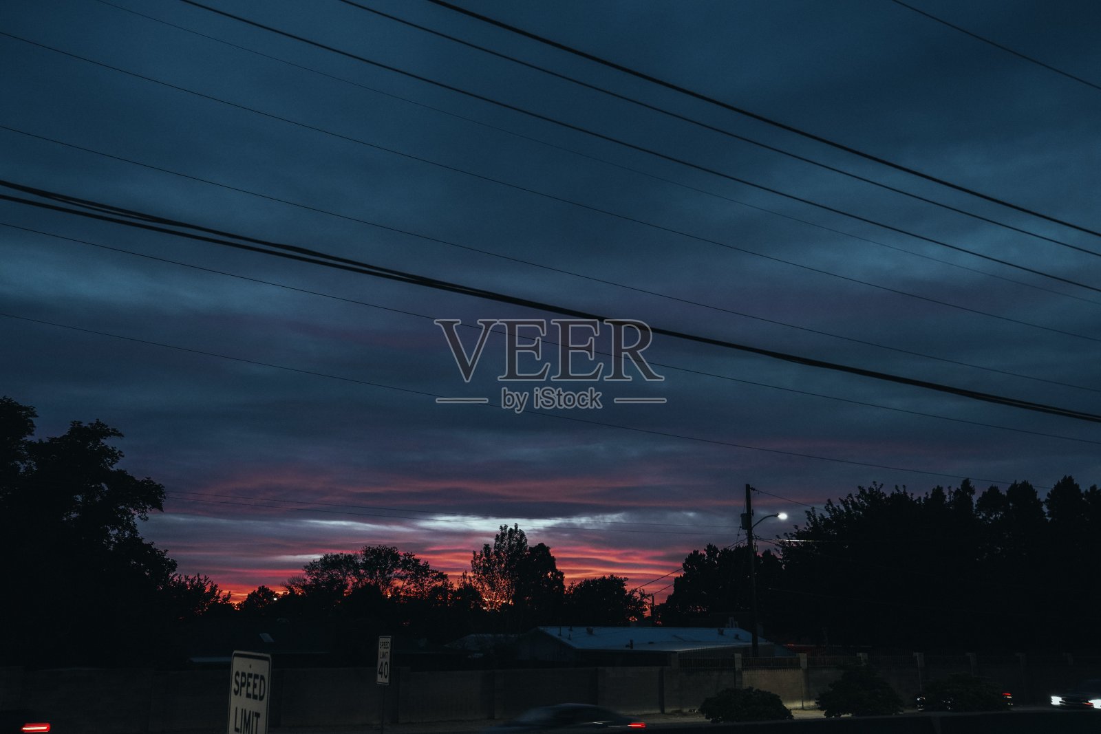 美丽的日落，树木的剪影衬托着深蓝色多云的天空照片摄影图片