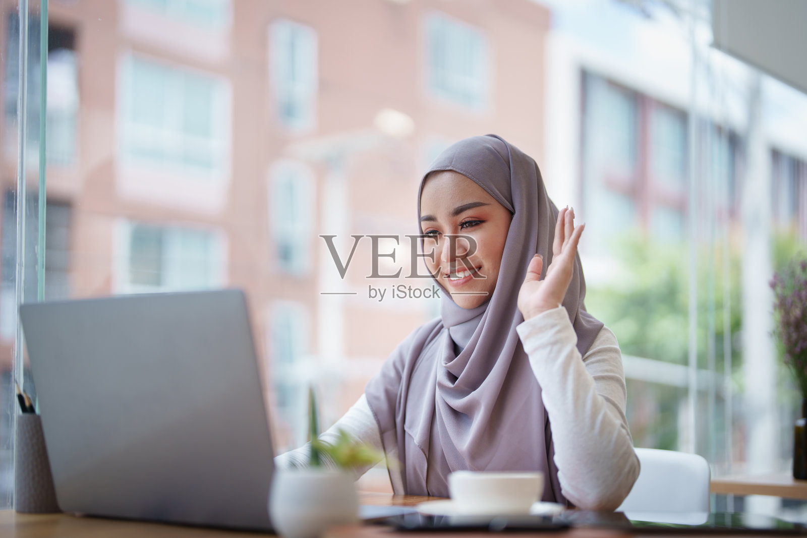 美丽的穆斯林妇女使用电脑通过视频会议欢迎与会者照片摄影图片