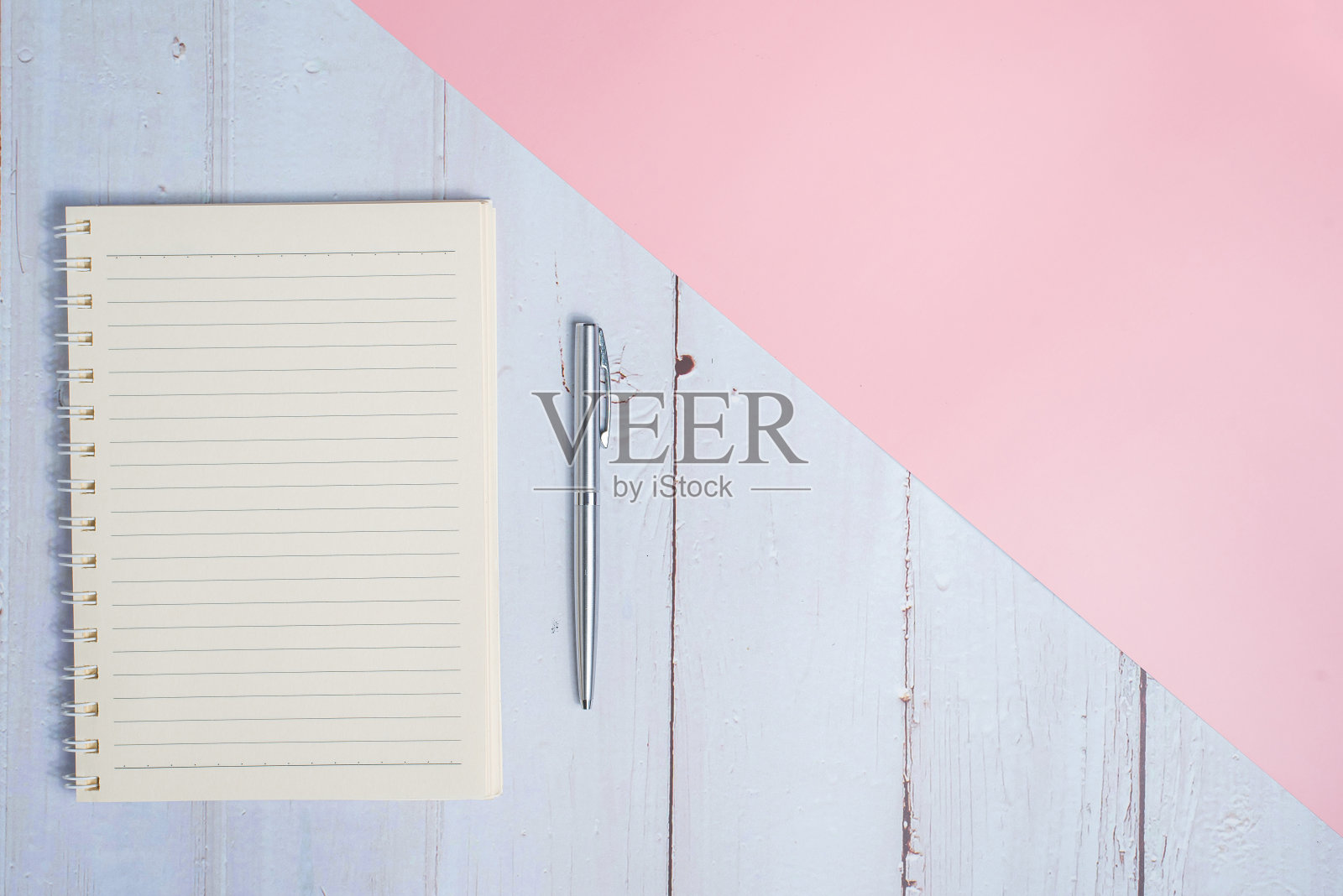 顶视图的笔记本与钢笔在木制桌子与粉红色的背景照片摄影图片