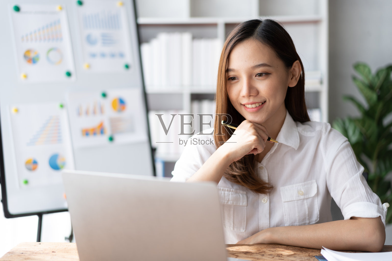 一位亚洲年轻的女商人在她的工作站的笔记本电脑上工作。商务人员雇员自由职业在线报告营销电子商务电话营销概念。照片摄影图片