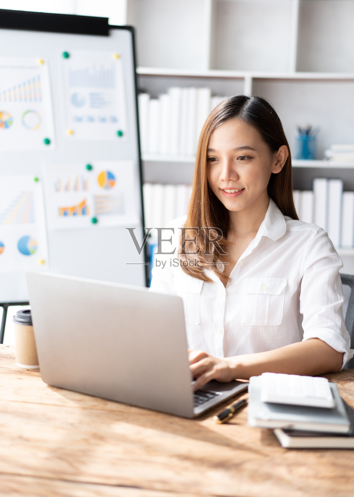 开朗的商务女士在办公室用笔记本电脑工作，亚洲快乐美丽的商务女士在正式的西装工作在工作场所。迷人的女职员办公室职员微笑。照片摄影图片