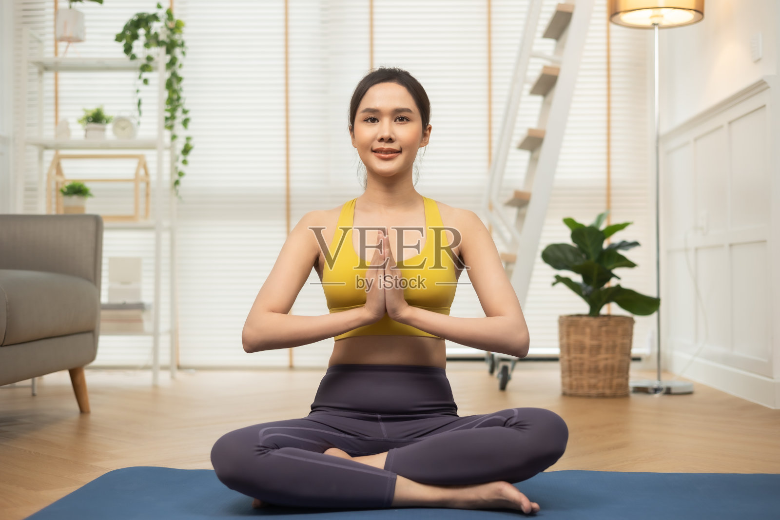 年轻的亚洲女子在家里做瑜伽伸展瑜伽。快乐的人呆在家里，在客厅做有氧运动，女孩做禁闭活动，在家里和教练锻炼健康。照片摄影图片