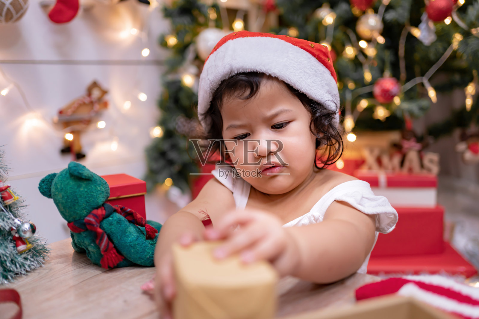 快乐的亚洲小女孩在圣诞节玩得很开心。孩子和父母在家里装饰圣诞树在假日。照片摄影图片