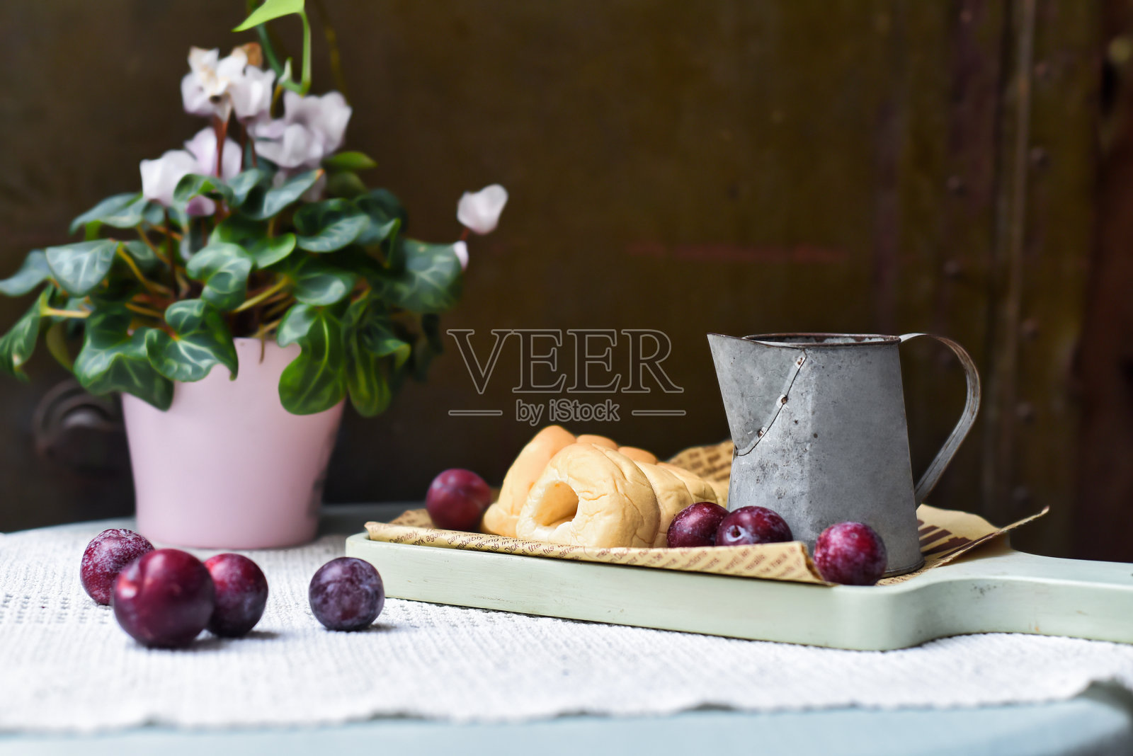 鲜奶油管与杯和梅子在编织布上黑色背景照片摄影图片