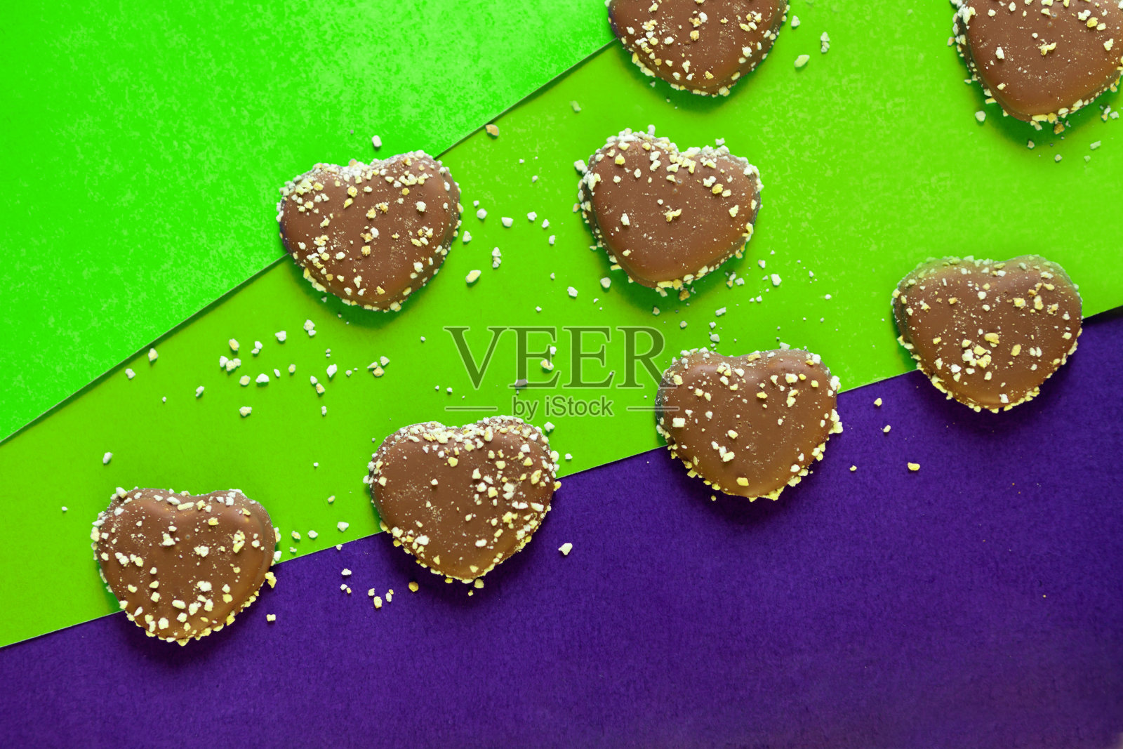 巧克力心形饼干与坚果在彩色的背景。平铺在彩色纸上。巧克力照片摄影图片