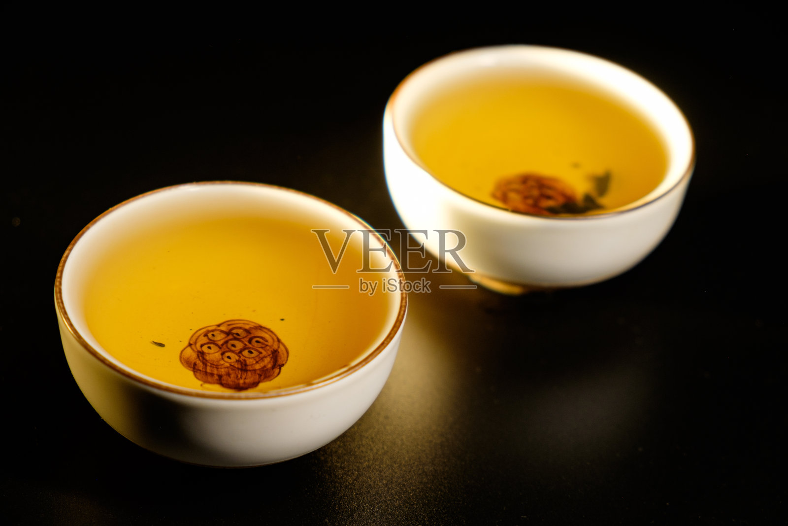 传统的日本、中国亚洲茶道概念。白色陶瓷茶杯，黑底荷花。副本的空间。照片摄影图片