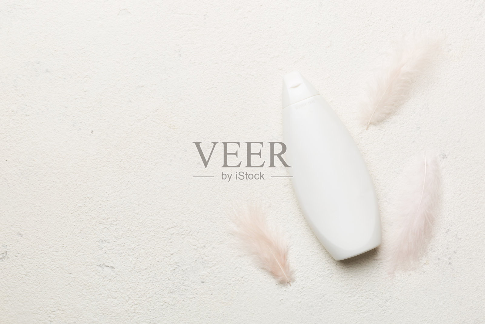 一套皮肤护理精华在粉色粉彩背景与鸵鸟羽毛。Spa化妆品，奶油罐，品牌模拟，顶视图与复制空间照片摄影图片