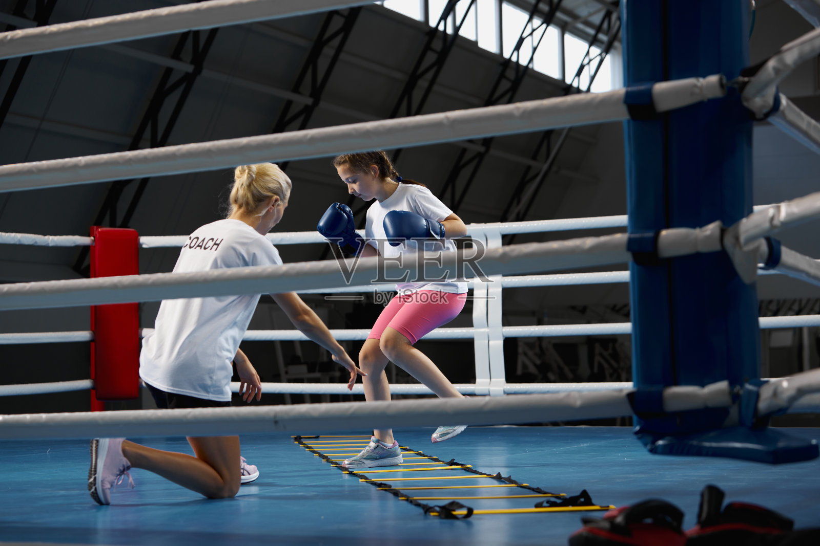 健身教练。学龄女孩，初级自由搏击训练与私人教练在健身房，室内。学习、挑战、运动、爱好、竞争的概念照片摄影图片