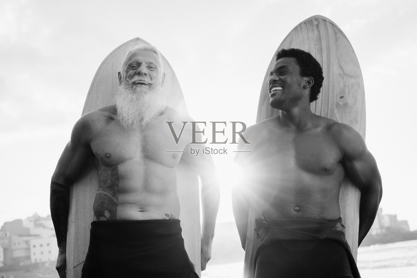 多种族的高级和年轻男子冲浪者在海滩冲浪训练后有乐趣-旅游假期-软焦点老人的脸-黑白编辑照片摄影图片