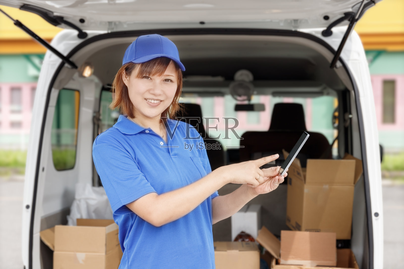 一位搬运轻货的女司机正在操作智能手机。照片摄影图片