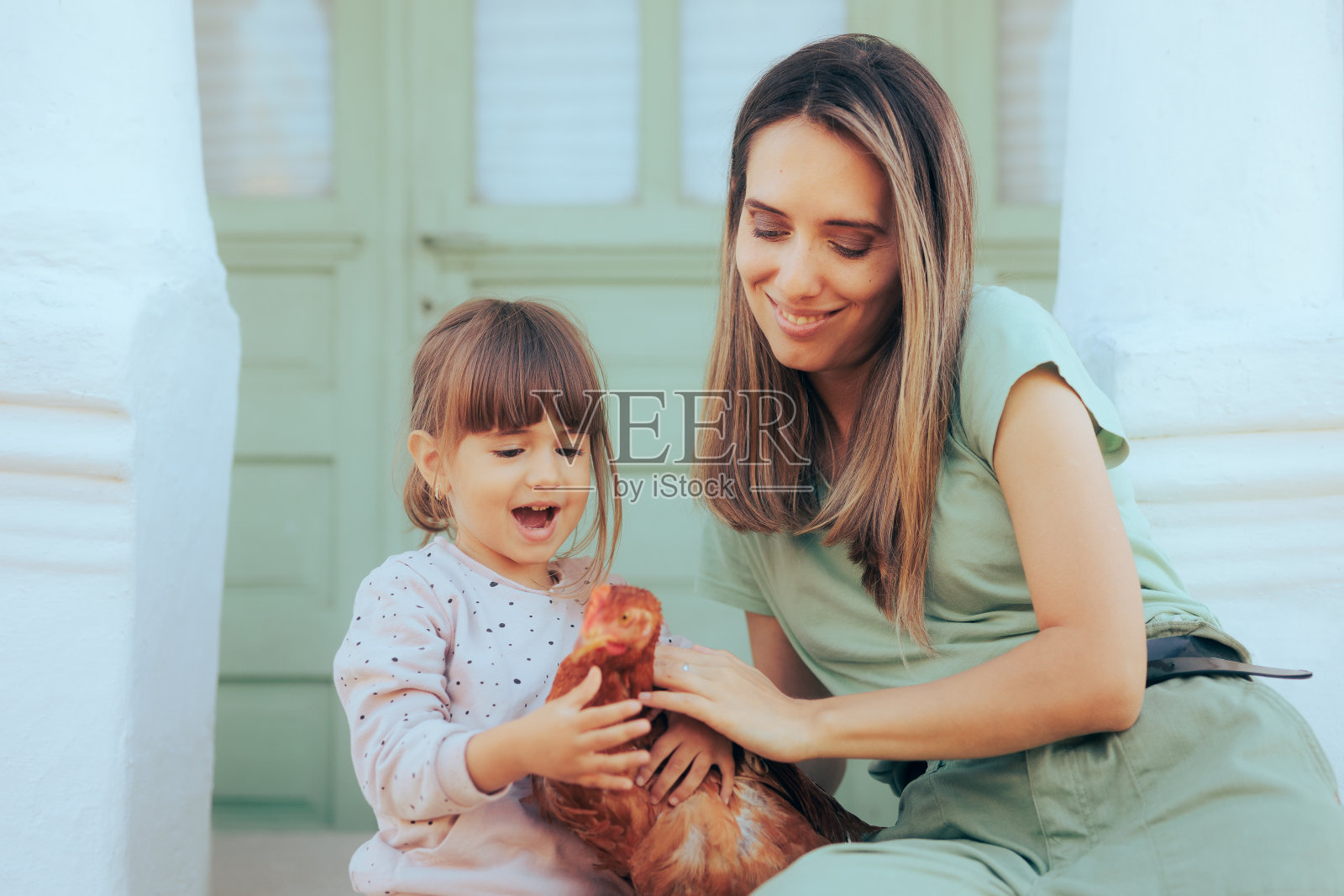 快乐的妈妈和女儿在抚摸小鸡照片摄影图片