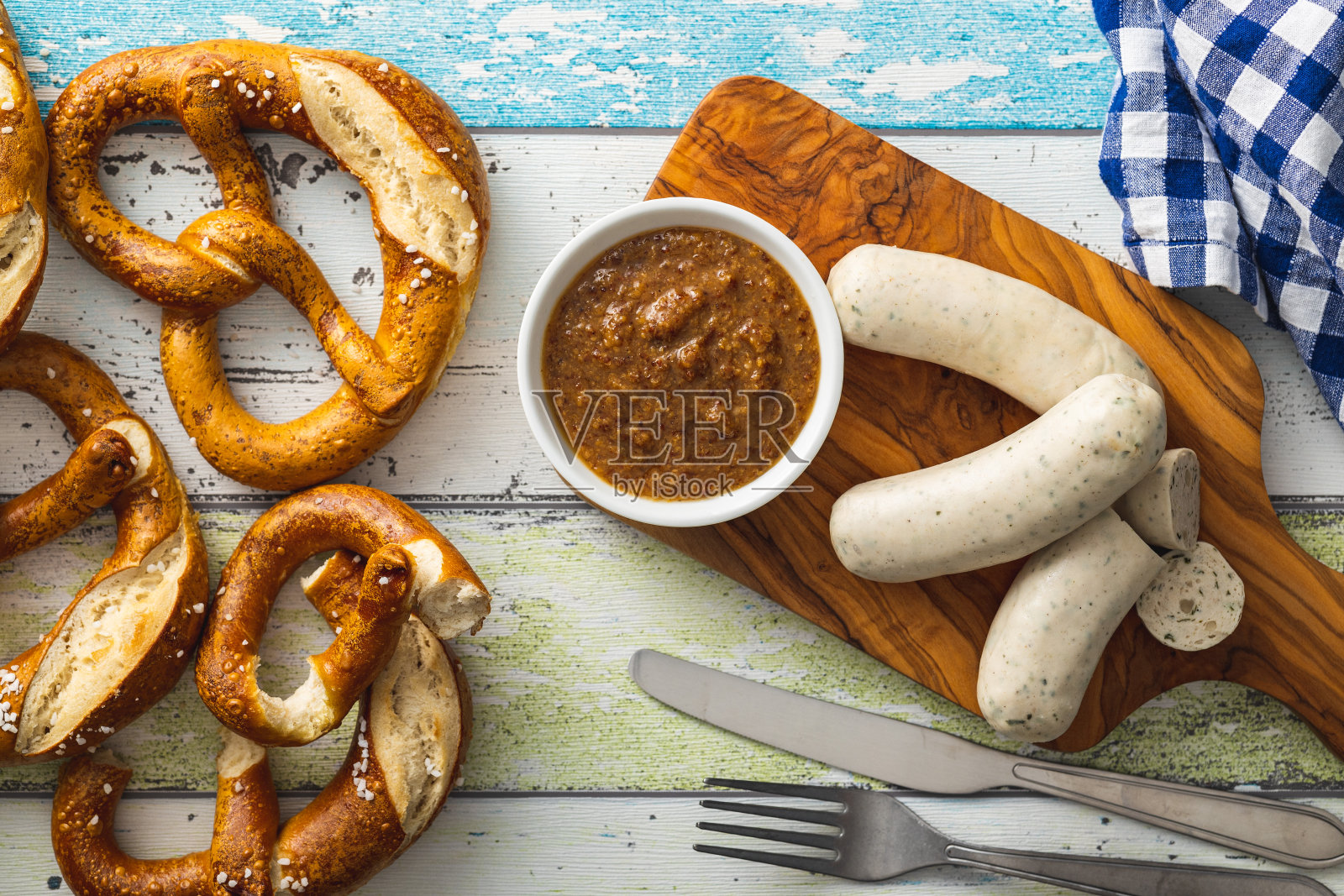 传统的巴伐利亚白香肠放在砧板上和椒盐卷饼。照片摄影图片