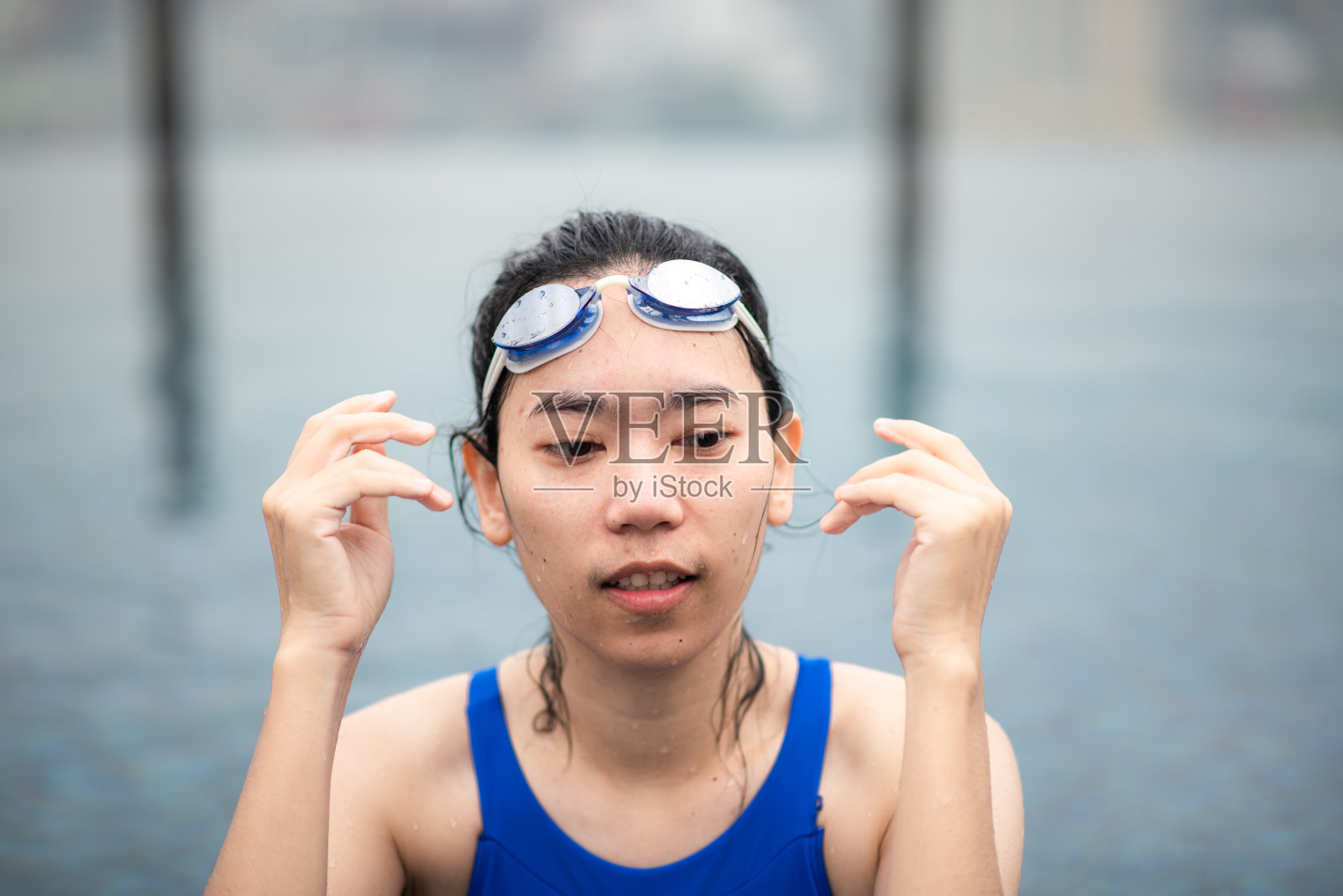 年轻的运动女性在游泳池游泳，健康的女性人在蓝色泳装与运动员的生活方式，水下积极健身比赛的女孩与泳镜在游泳池照片摄影图片