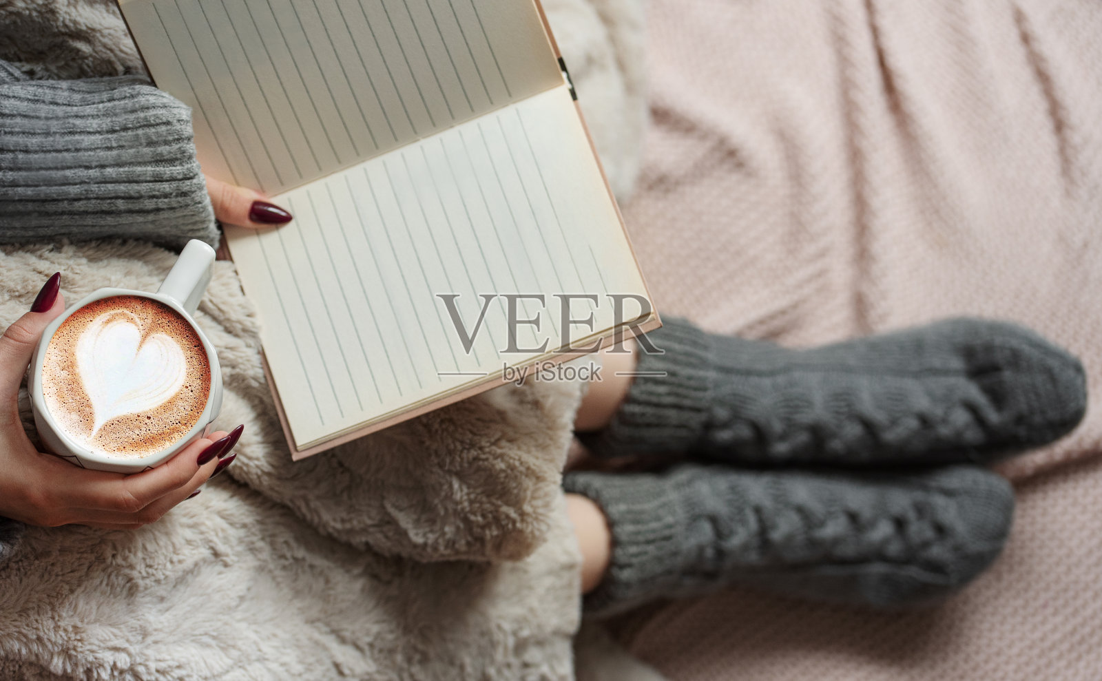 舒适的家，女人盖着温暖的毯子，喝着咖啡，读着书。照片摄影图片