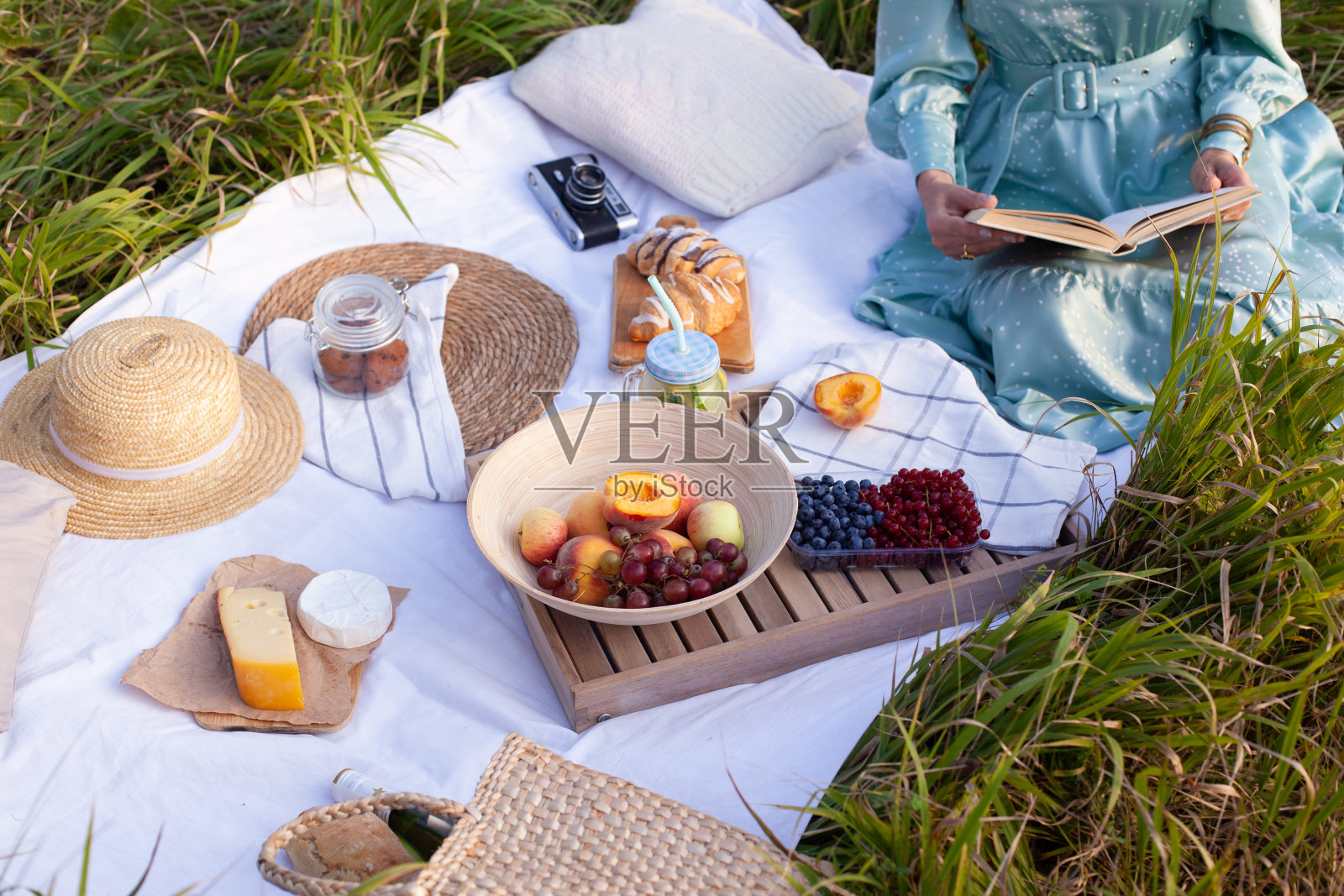 一名身穿蓝色连衣裙的女子坐在公园里野餐，全景尽收眼底照片摄影图片