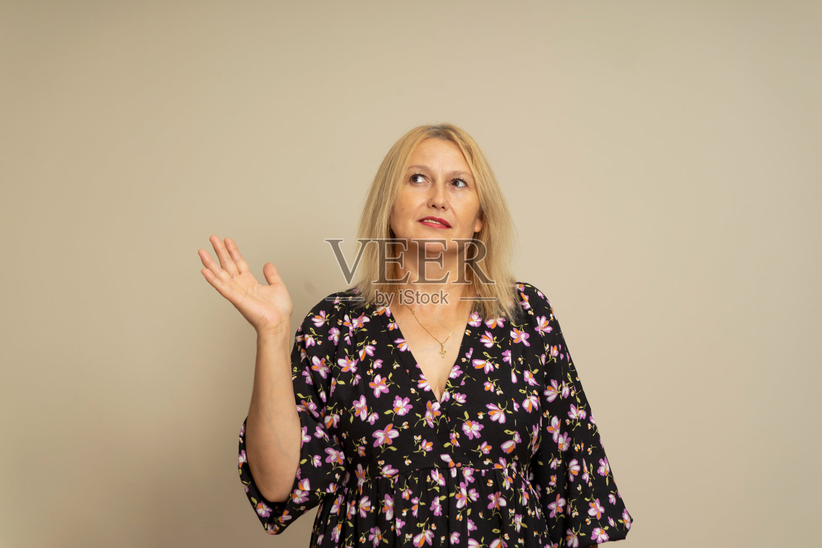 美丽的女人穿着深色图案的衣服站在米色的背景下微笑着友好地伸出手或握手提供一些东西作为问候和欢迎。成功的事业。照片摄影图片