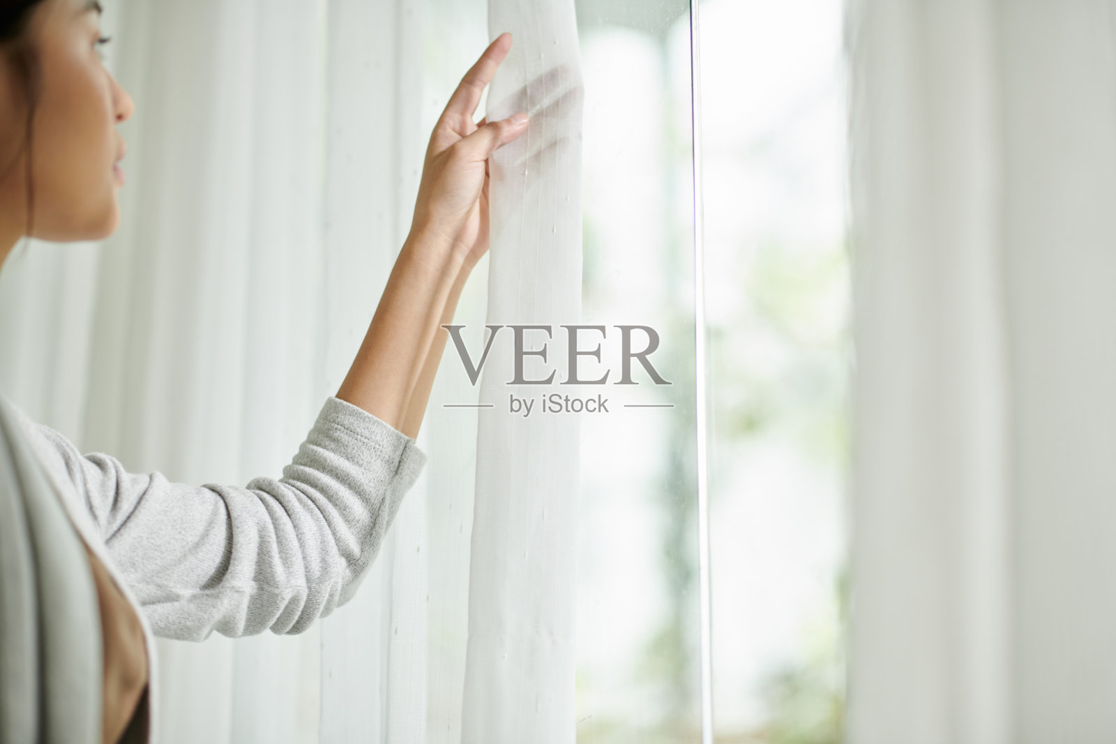 打开窗帘的年轻女子照片摄影图片