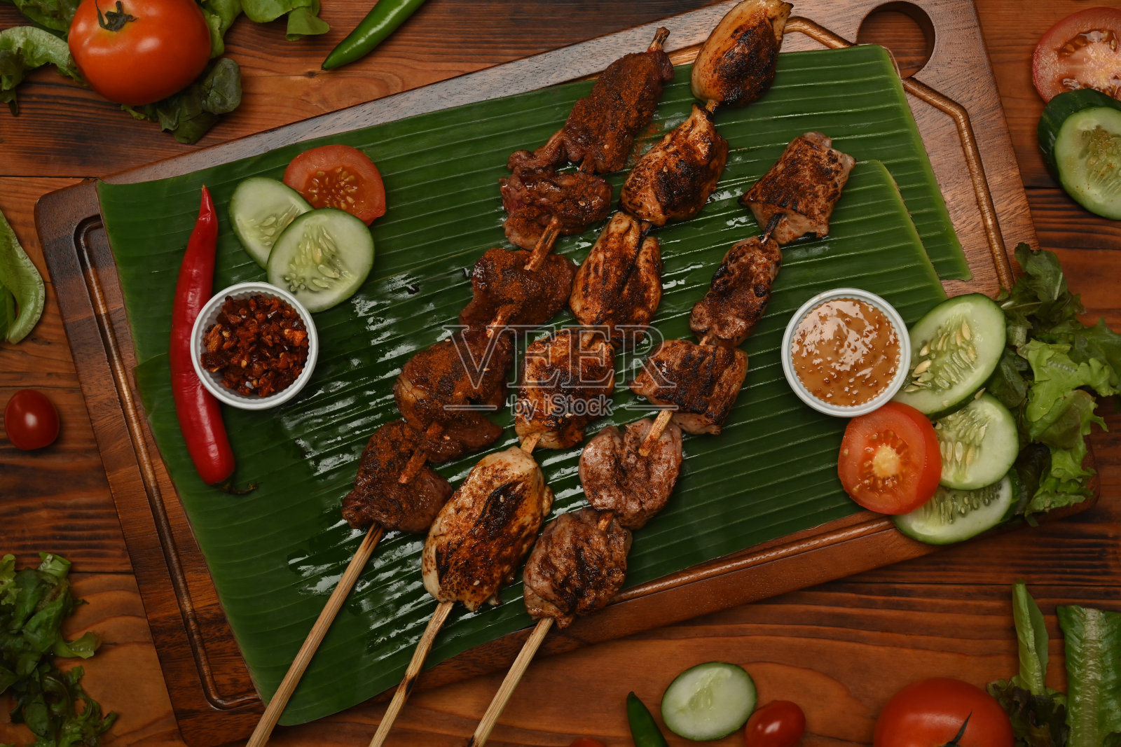 麻辣可口的街头小吃，花椒烤肉和芭蕉叶蔬菜。照片摄影图片