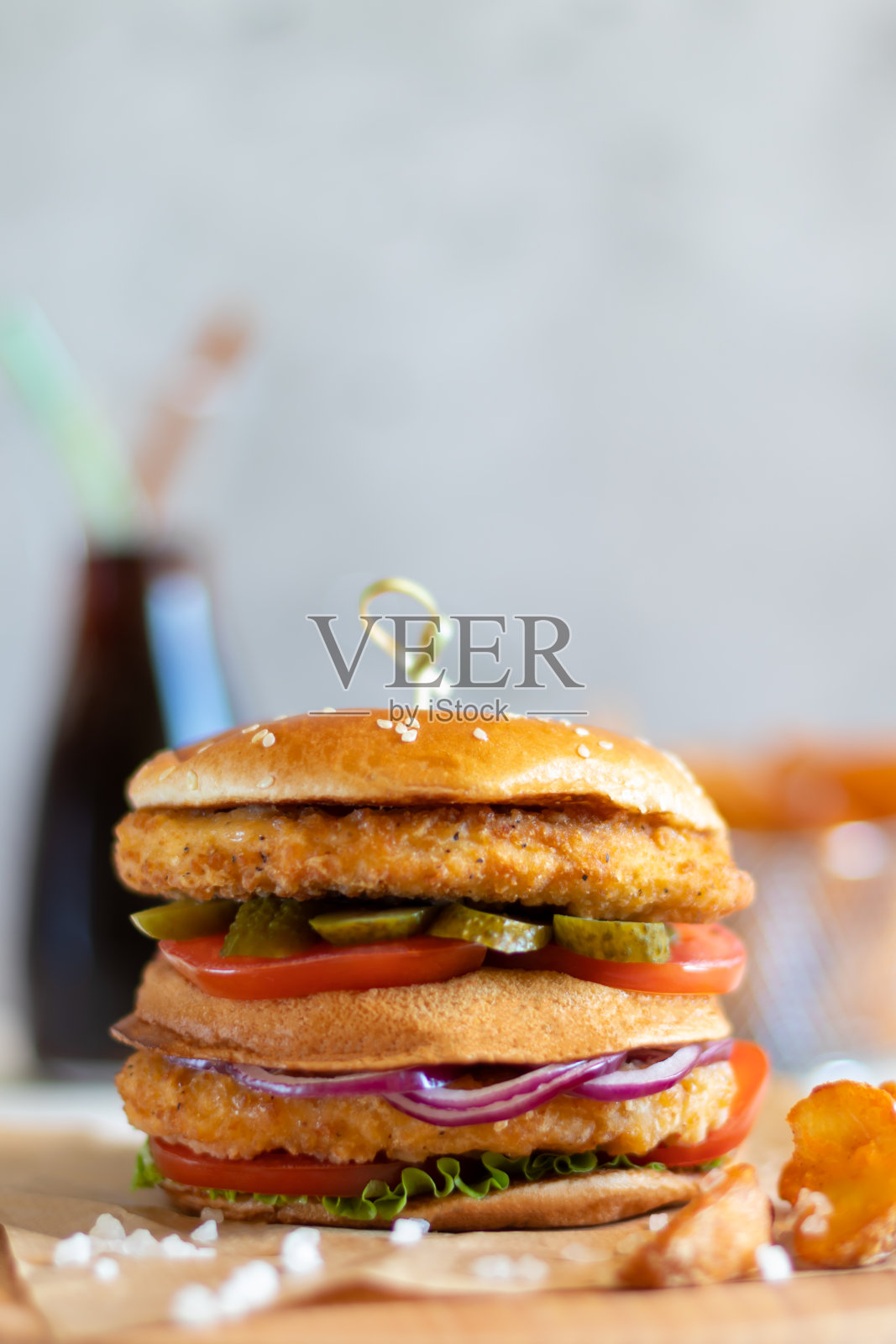 鸡肉汉堡配一瓶可口可乐，背景是土豆角照片摄影图片