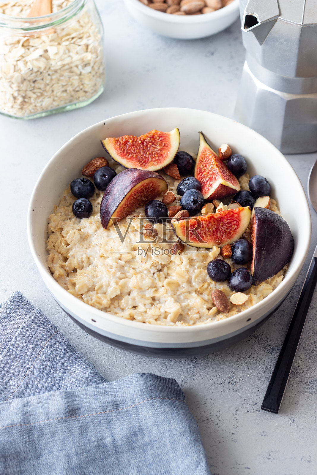 燕麦粥加无花果、蓝莓、杏仁和蜂蜜。健康饮食。素食。早餐。照片摄影图片