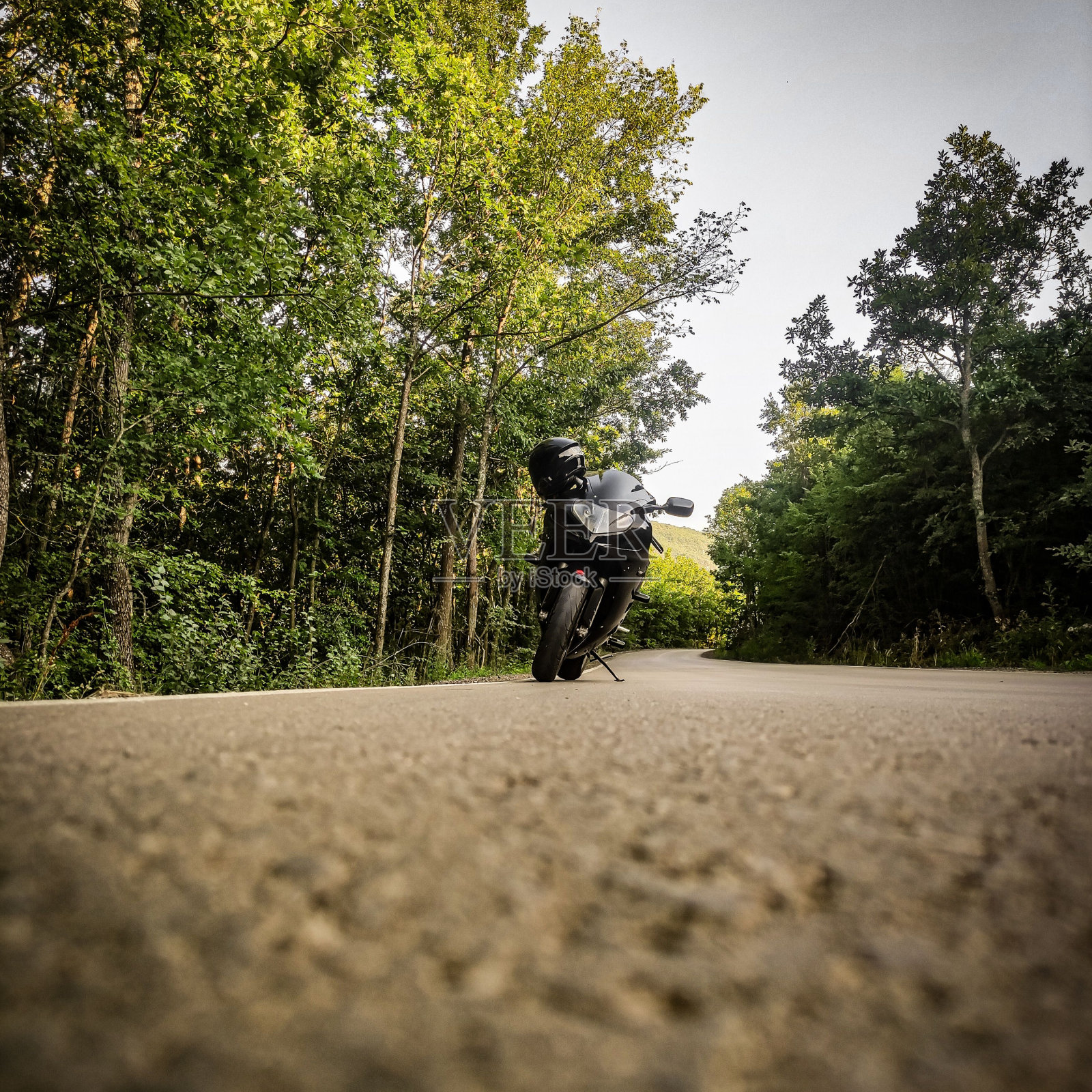 戴着头盔的黑色摩托车停在穿过公园的路上照片摄影图片