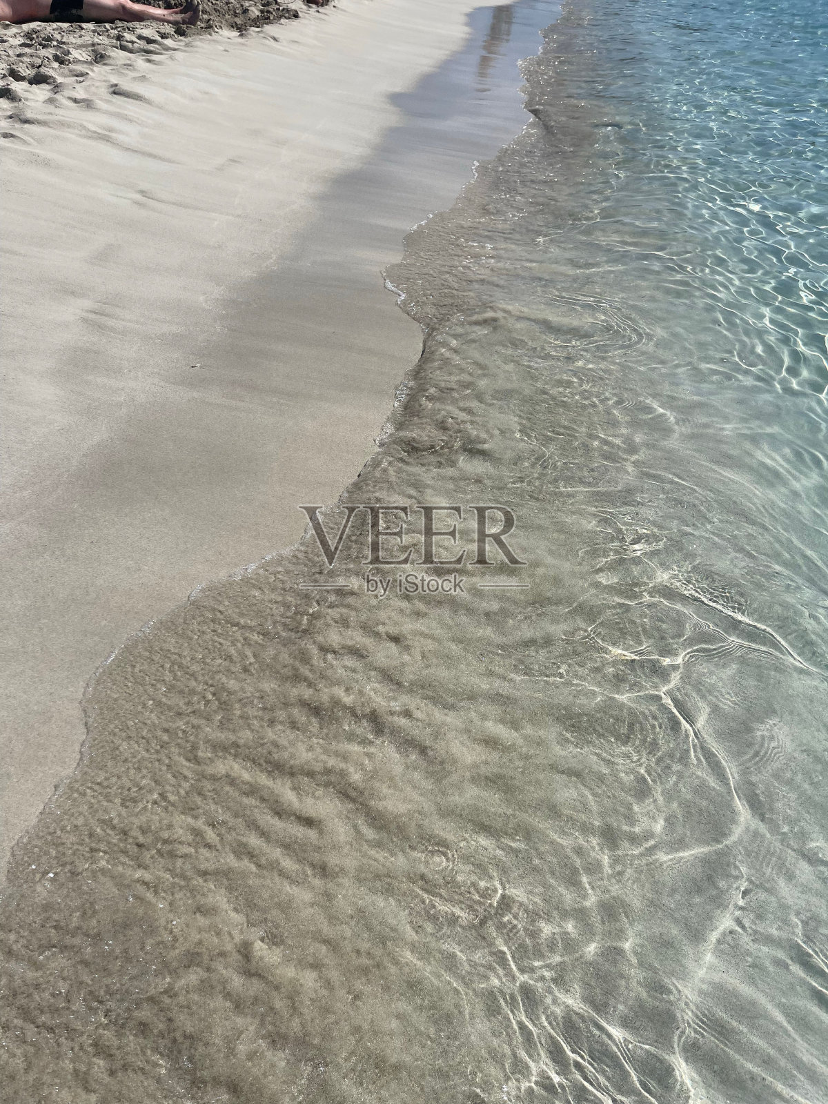 在一个阳光灿烂的日子里，沙滩对着蓝色的大海垂直拍摄照片摄影图片