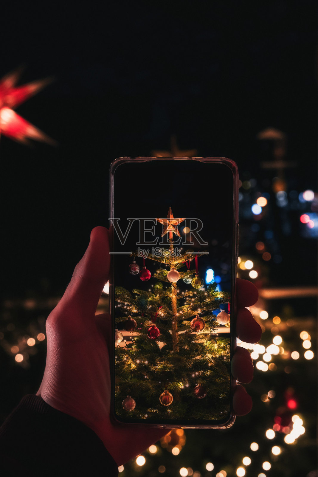 垂直拍摄的智能手机在晚上拍摄一棵被点亮的圣诞树照片摄影图片