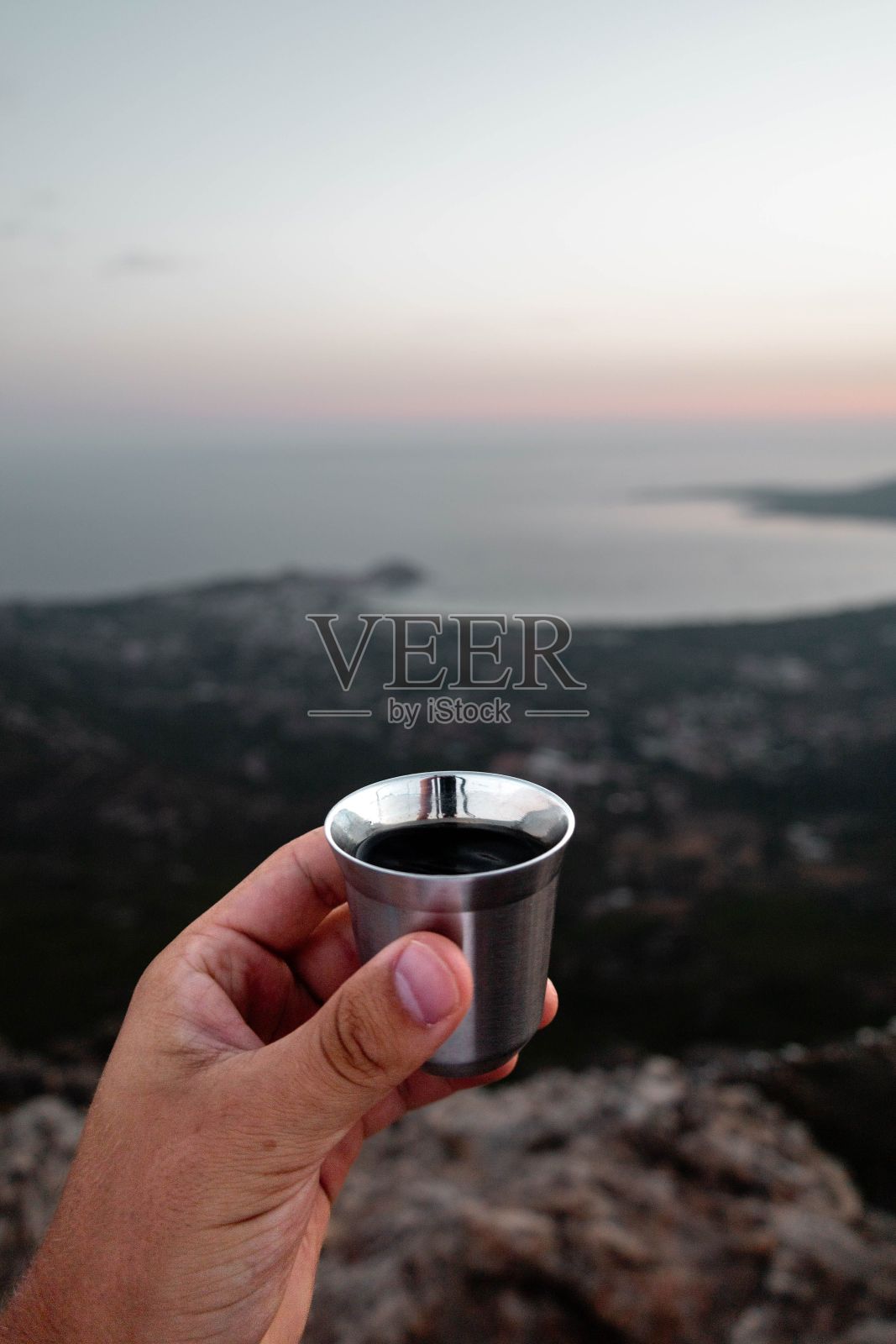 一个男人拿着一个银杯，背景是大海和海岸照片摄影图片