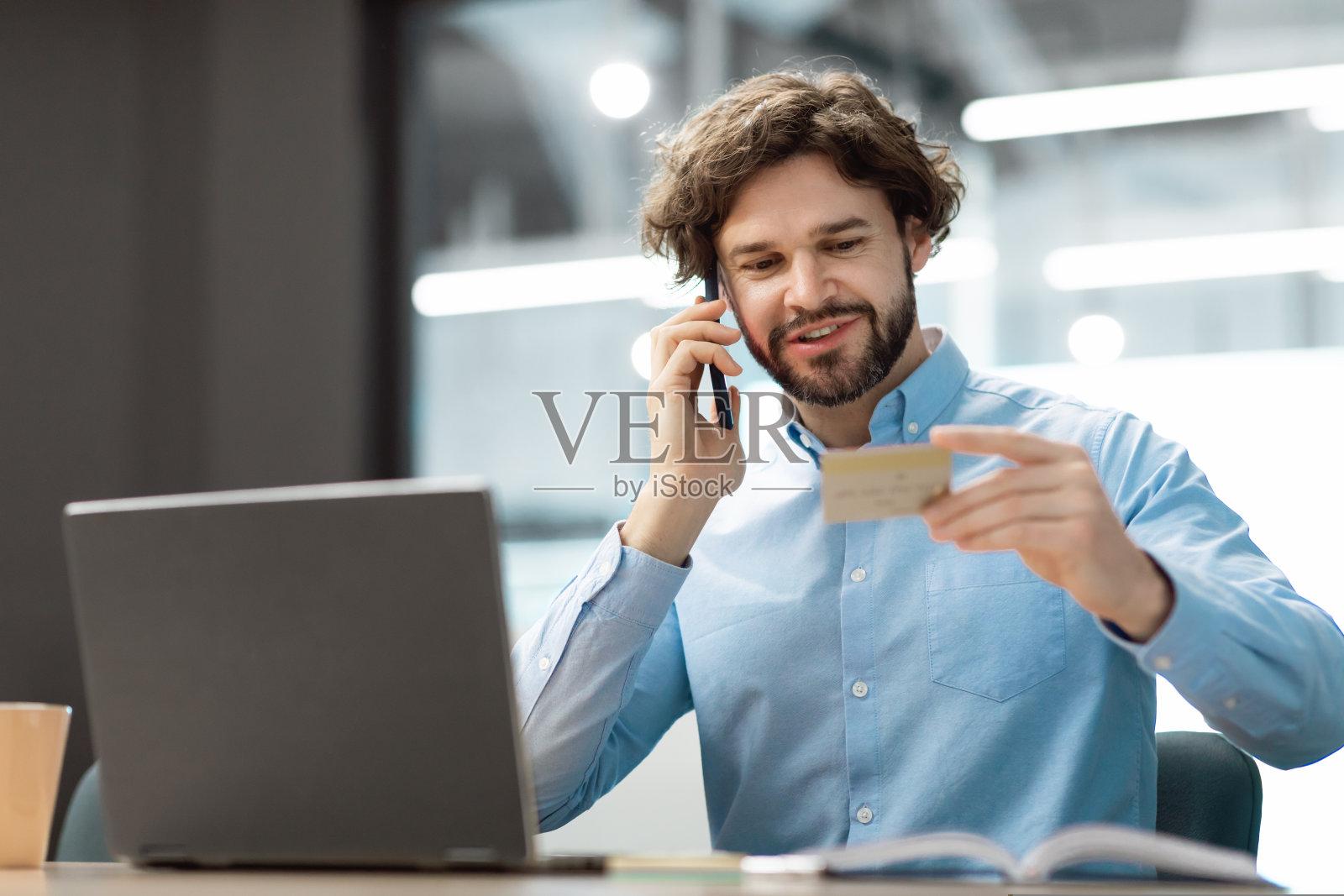 微笑的男子使用信用卡在智能手机上通话照片摄影图片