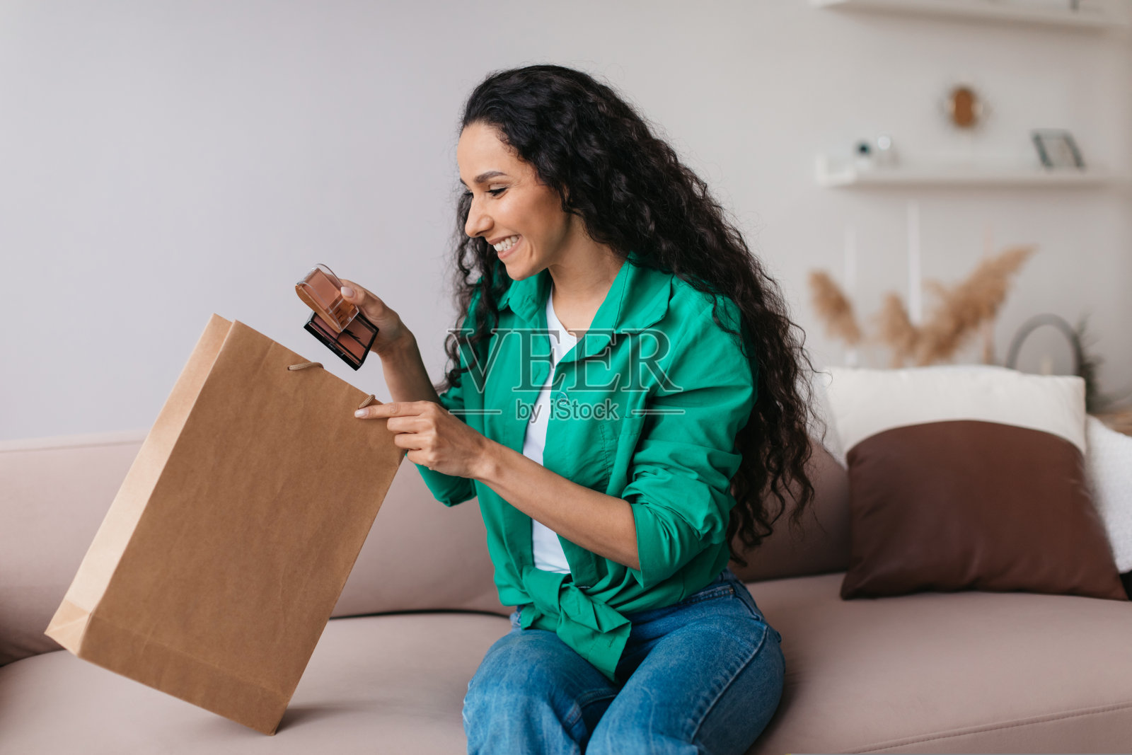 快乐的女人拿着化妆品，打开包坐在家里照片摄影图片